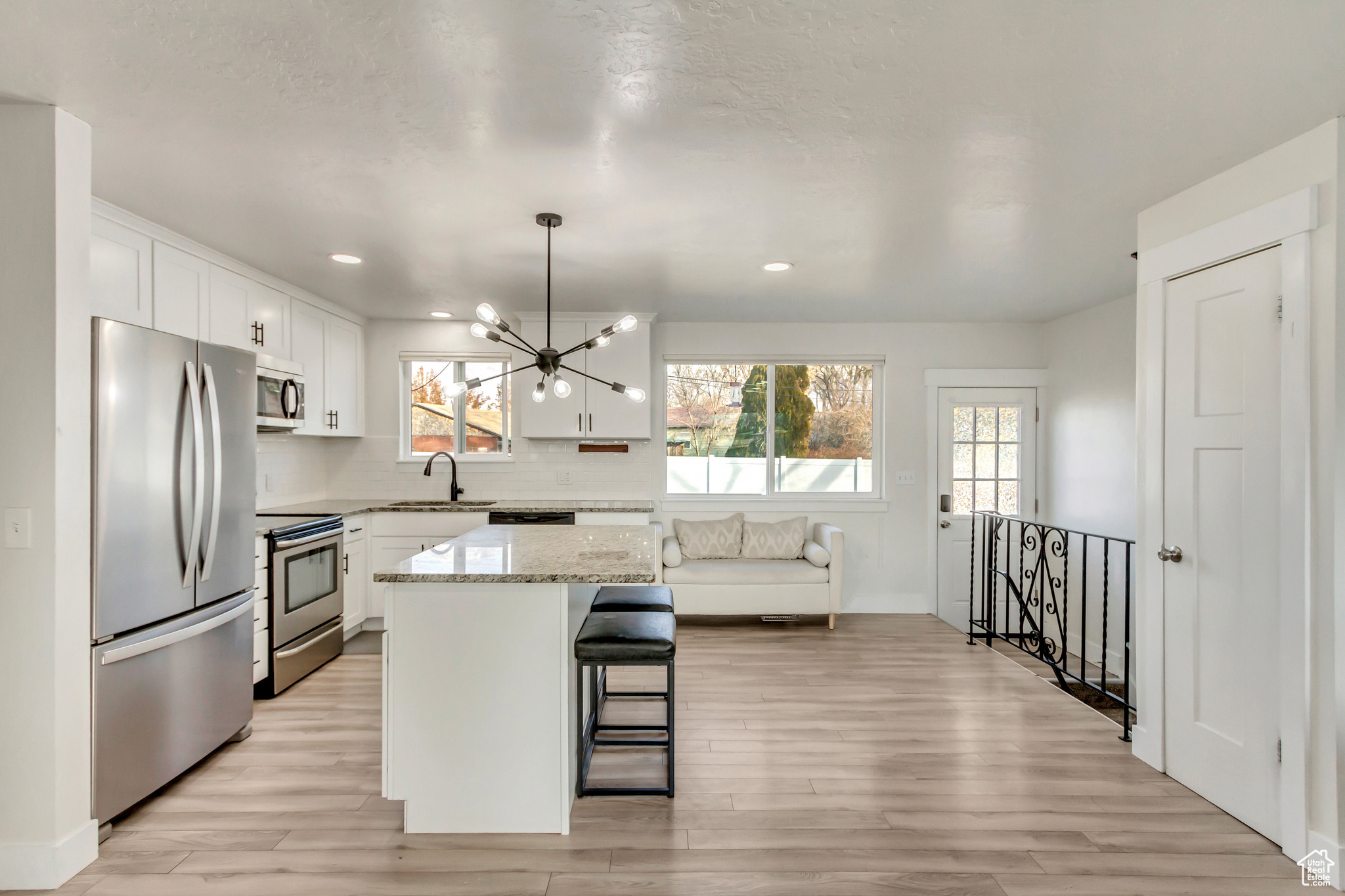 Kitchen with white cabinetry, sink, a center island, light hardwood / wood-style floors, and appliances with stainless steel finishes