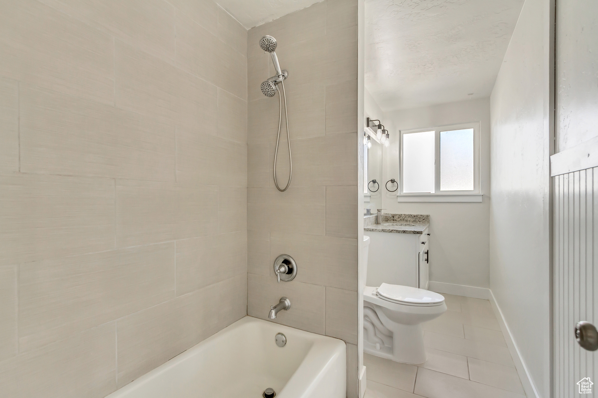 Full bathroom featuring tile patterned floors, vanity, tiled shower / bath combo, and toilet