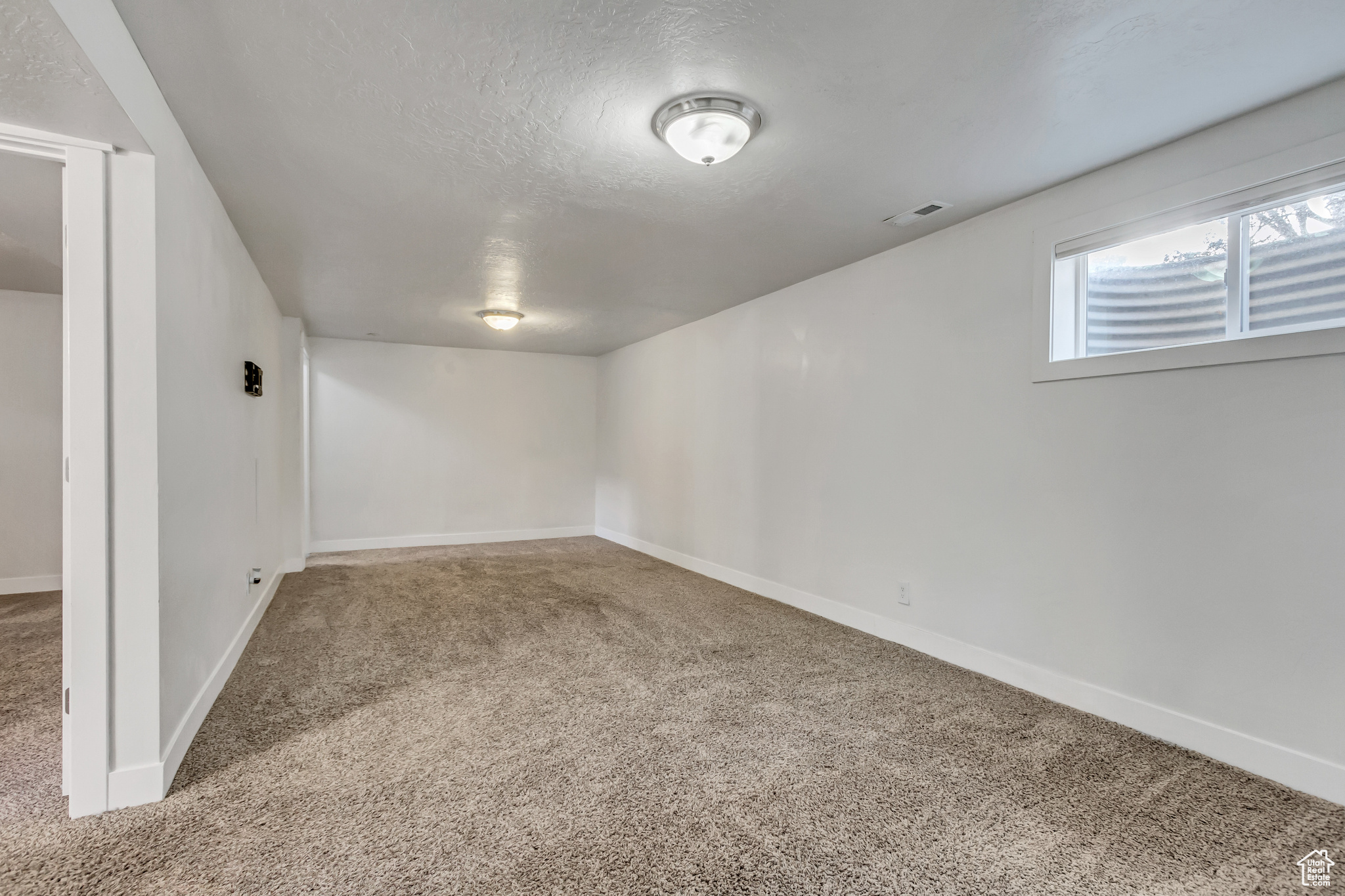 Basement with carpet floors and a textured ceiling