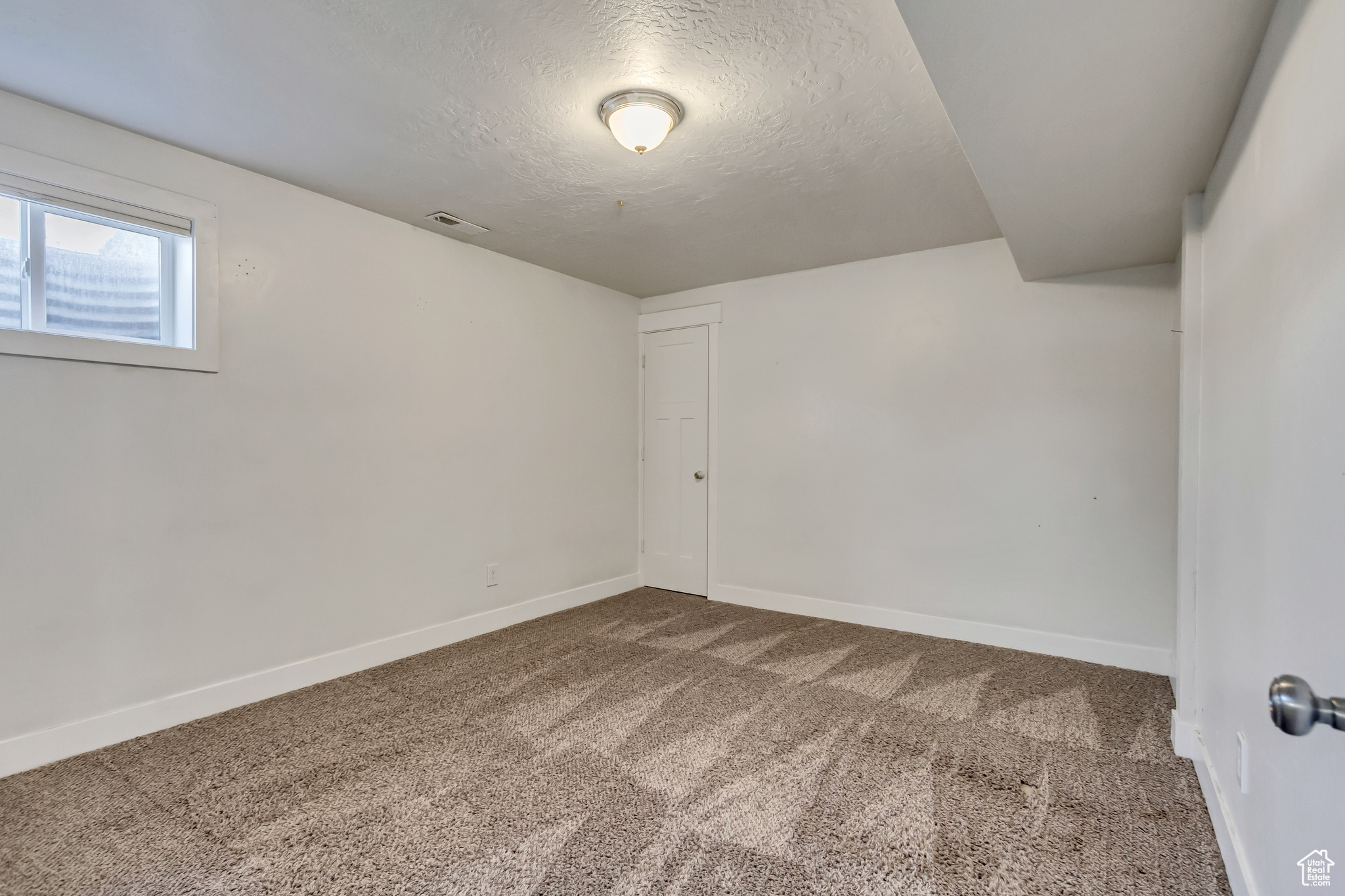 Carpeted spare room with a textured ceiling