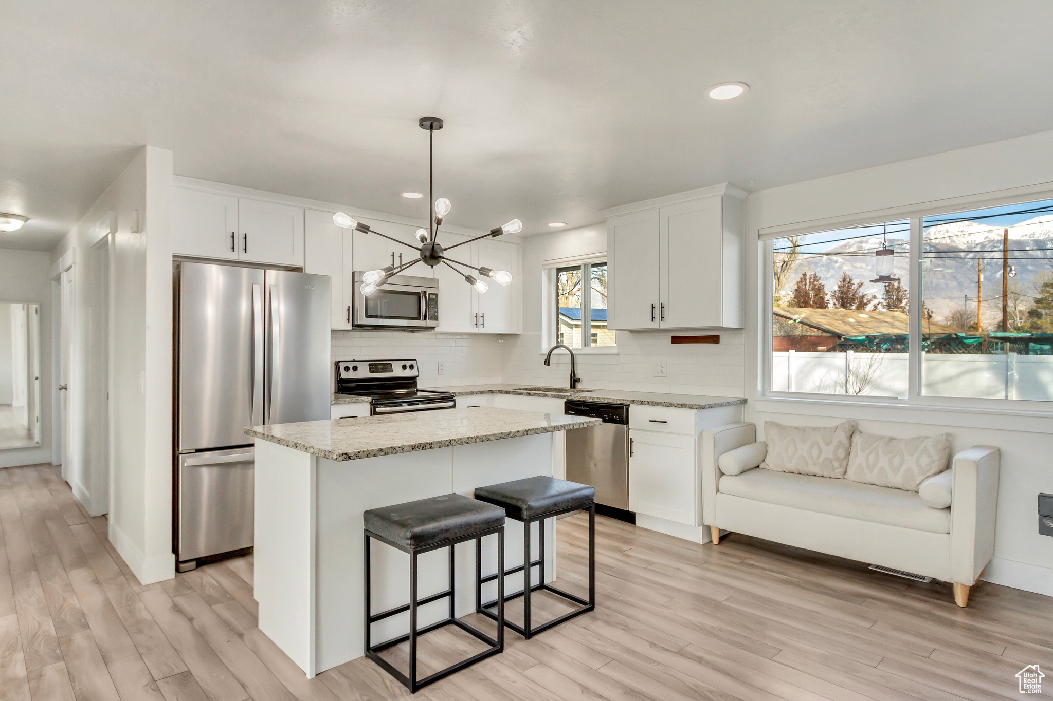 Kitchen with a wealth of natural light, a kitchen island, light wood-type flooring, and appliances with stainless steel finishes