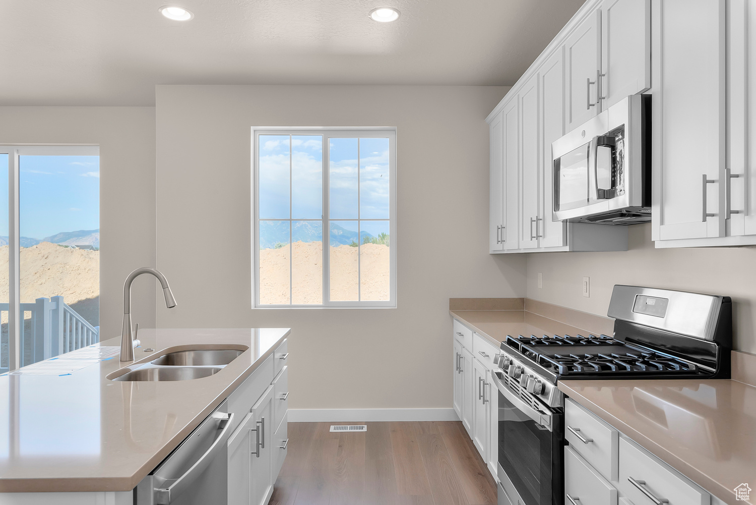 Kitchen featuring white cabinetry, light wood-type flooring, appliances with stainless steel finishes, and sink