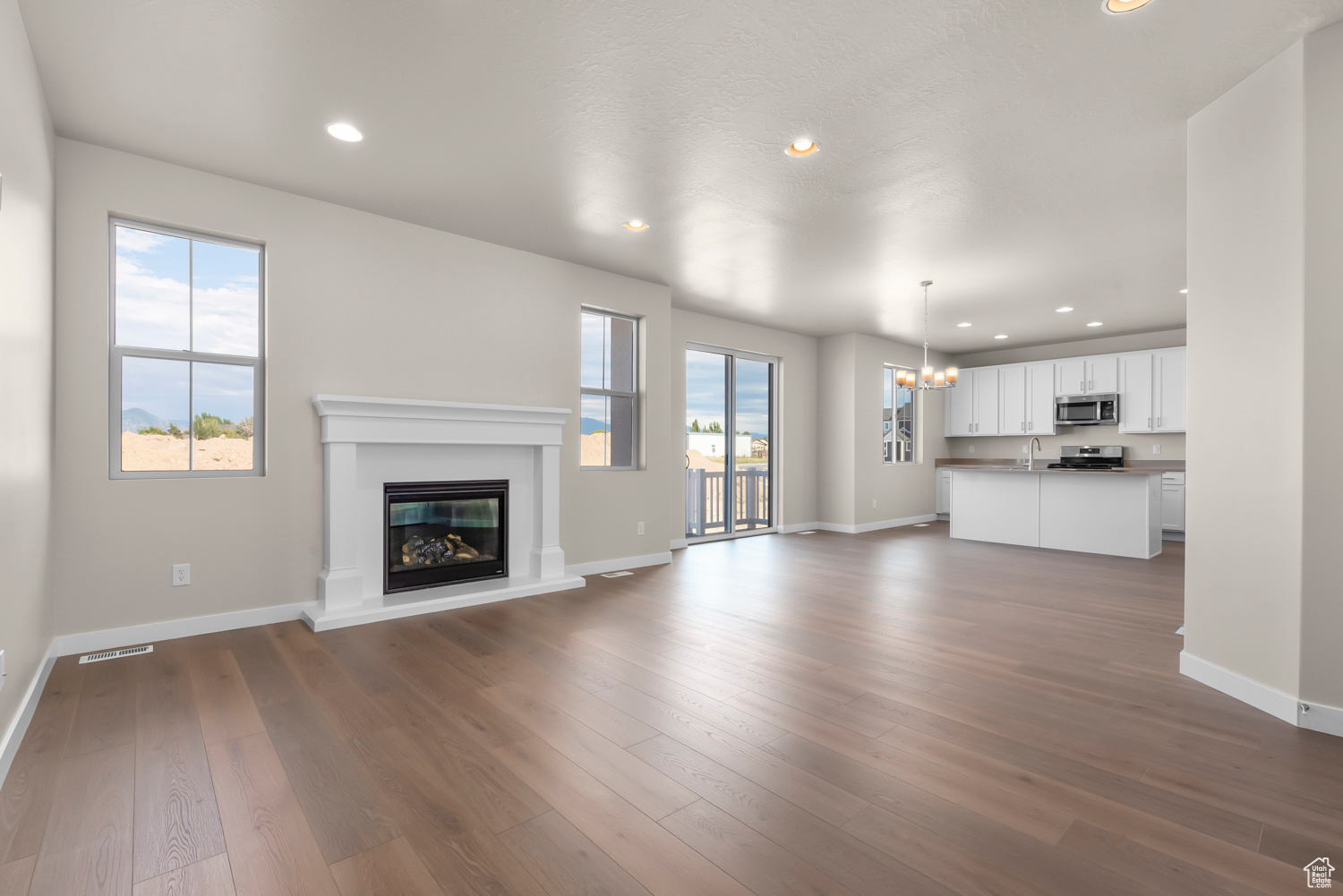 Unfurnished living room featuring dark hardwood / wood-style flooring, a chandelier, and sink