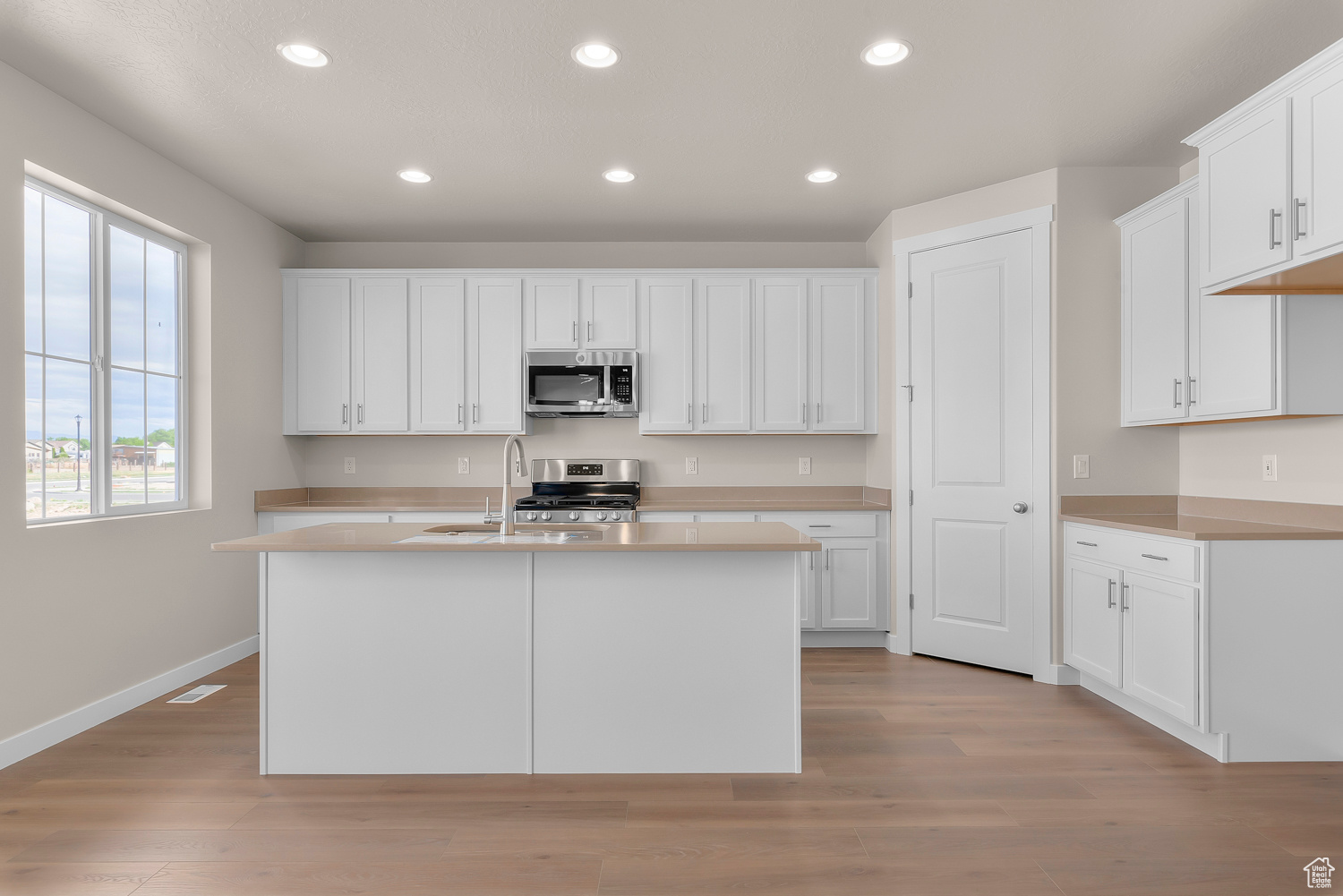 Kitchen with white cabinetry, appliances with stainless steel finishes, sink, and light wood-type flooring