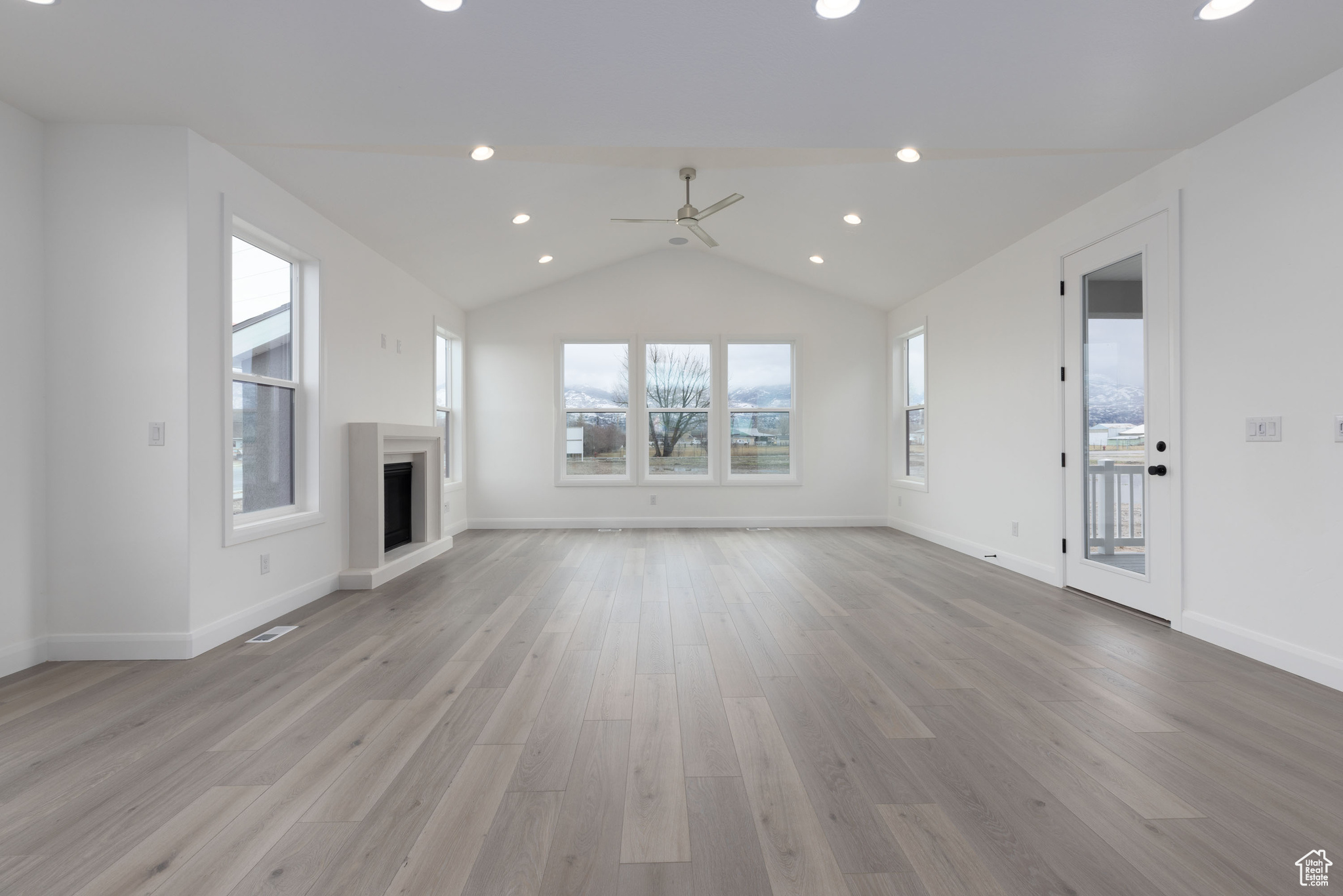 Unfurnished living room with lofted ceiling, ceiling fan, and light hardwood / wood-style flooring