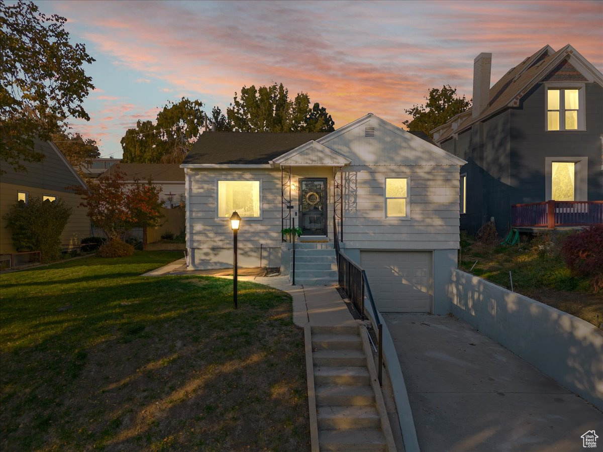 View of front of house with a garage and a yard