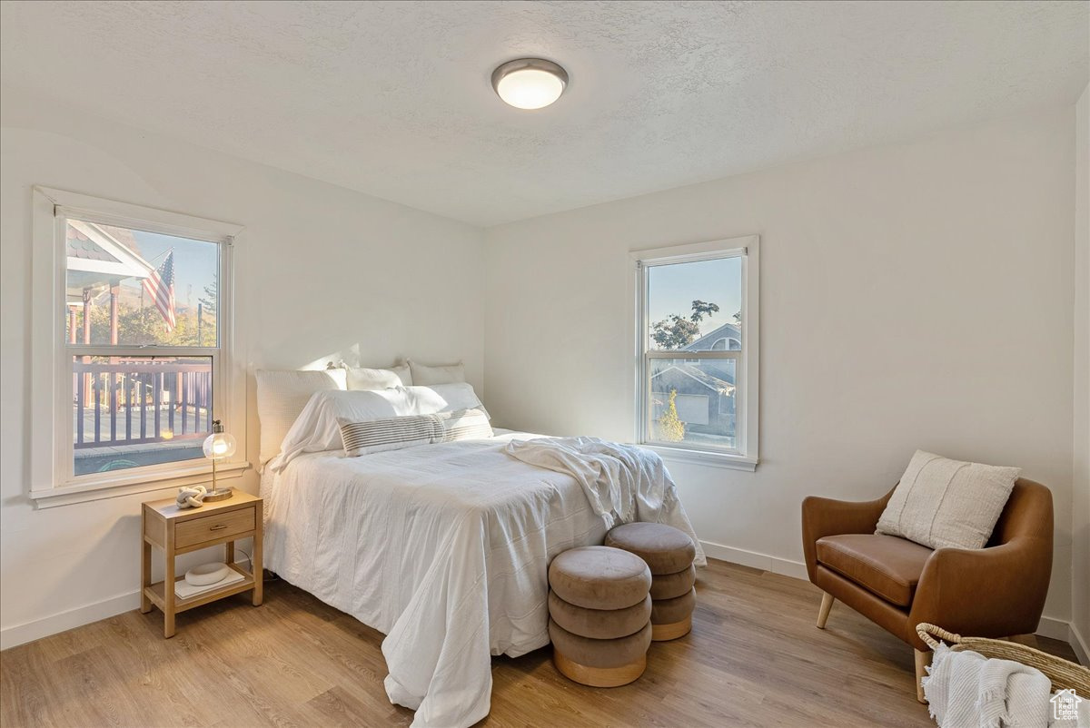 Bedroom with a textured ceiling and light hardwood / wood-style floors