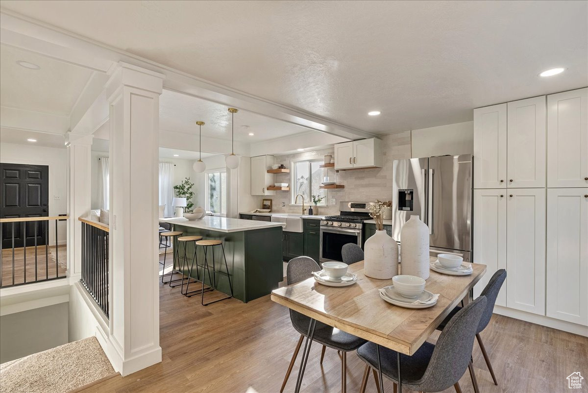 Dining area with light hardwood / wood-style floors, sink, and decorative columns