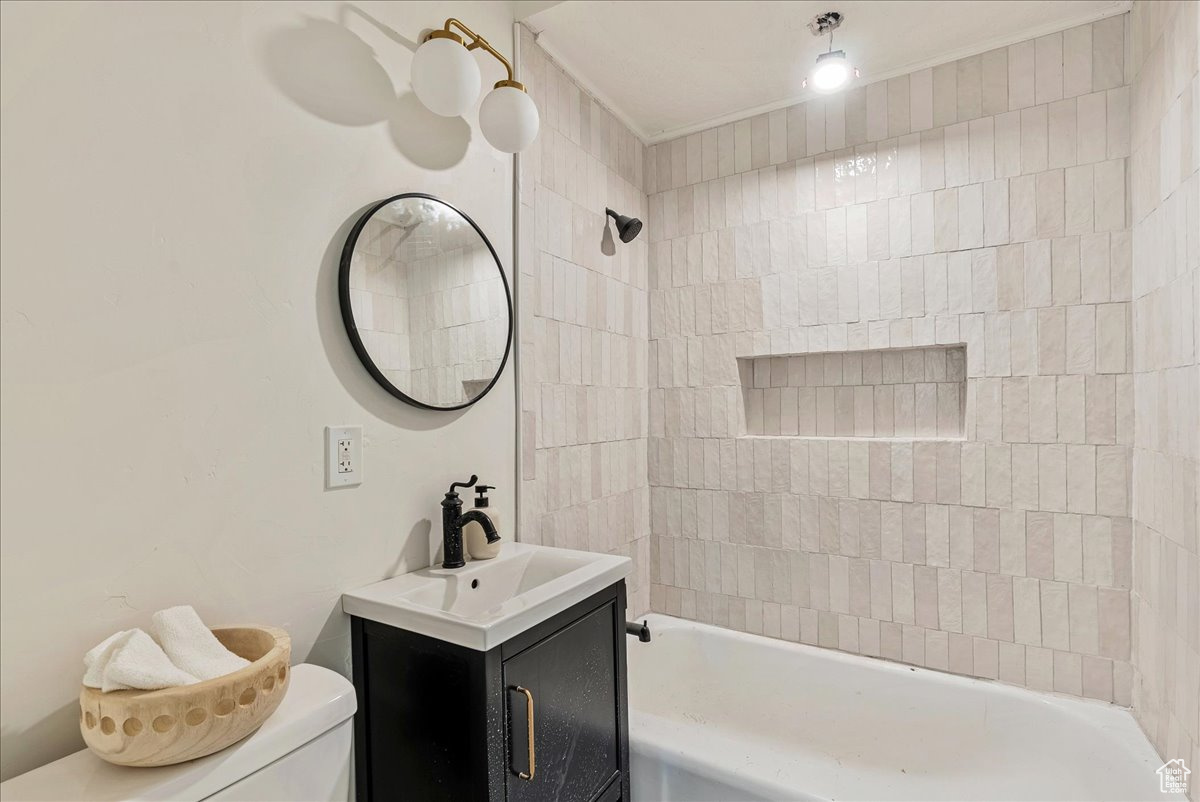 Full bathroom featuring crown molding, vanity, toilet, and tiled shower / bath