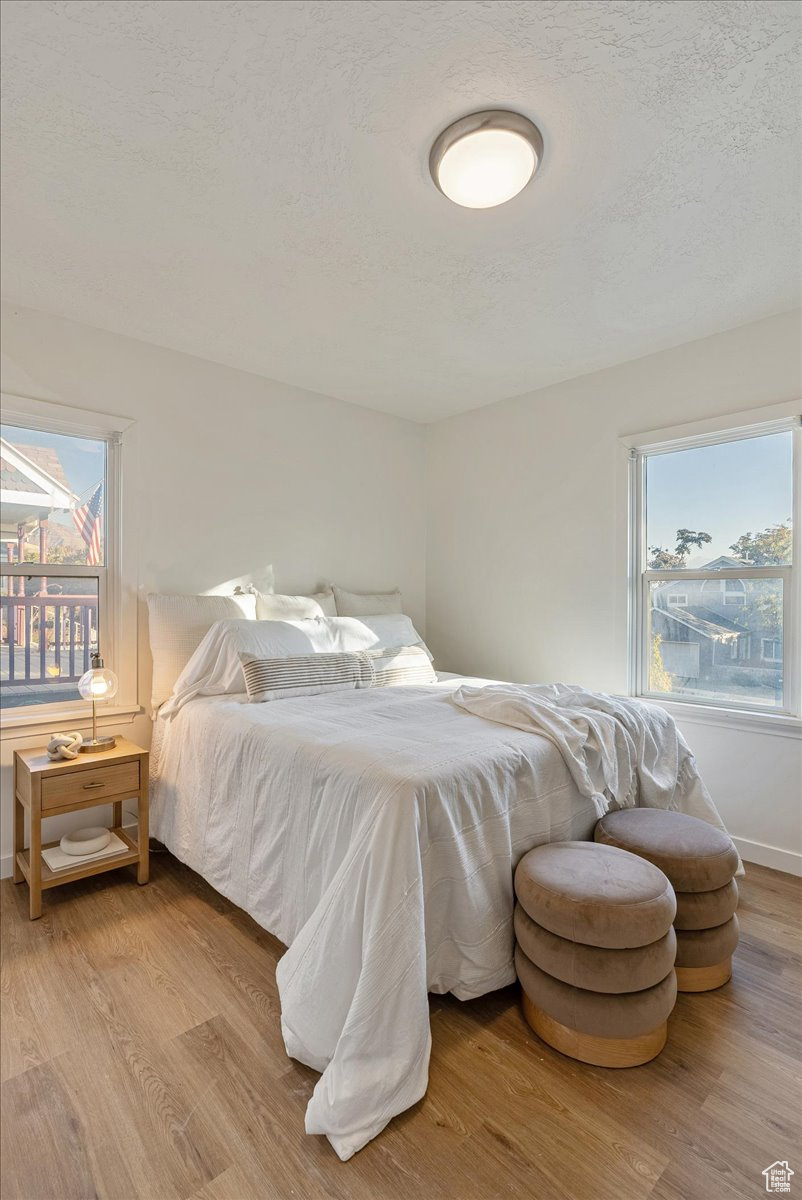 Bedroom with a textured ceiling and light hardwood / wood-style flooring