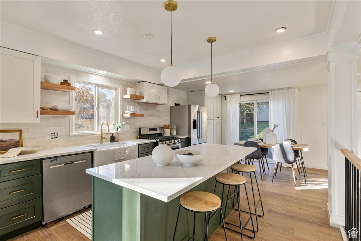 Kitchen featuring plenty of natural light, tasteful backsplash, white cabinetry, and stainless steel appliances