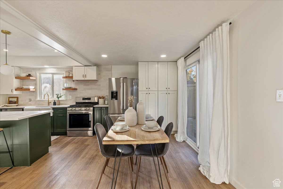 Dining room featuring beam ceiling, light hardwood / wood-style floors, and plenty of natural light