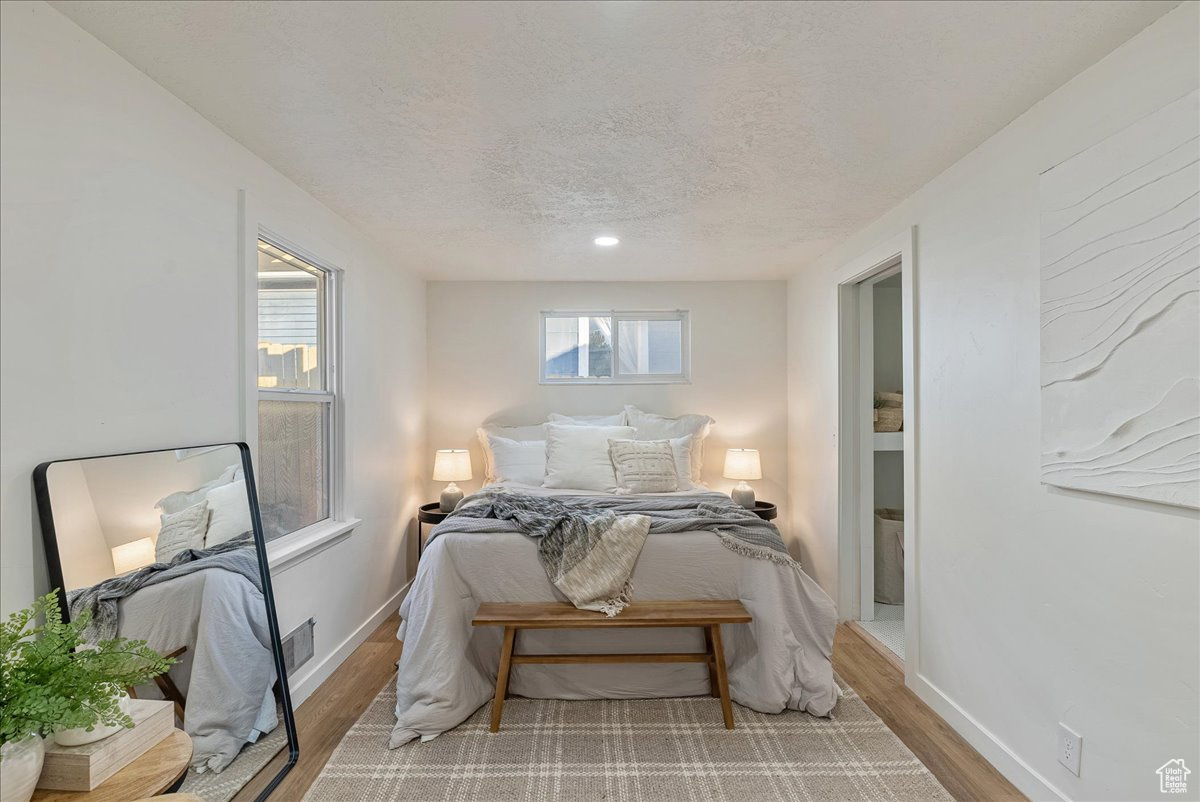 Bedroom with light hardwood / wood-style floors and a textured ceiling