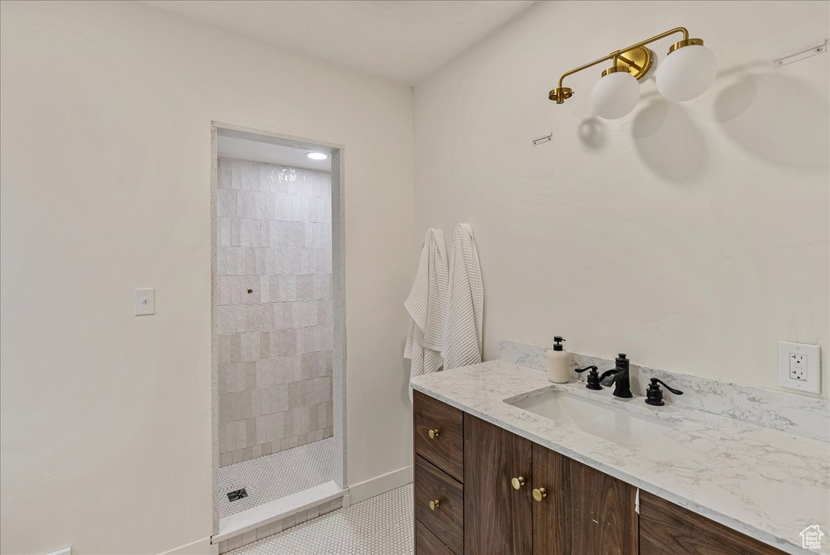 Bathroom with tiled shower, tile patterned flooring, and vanity