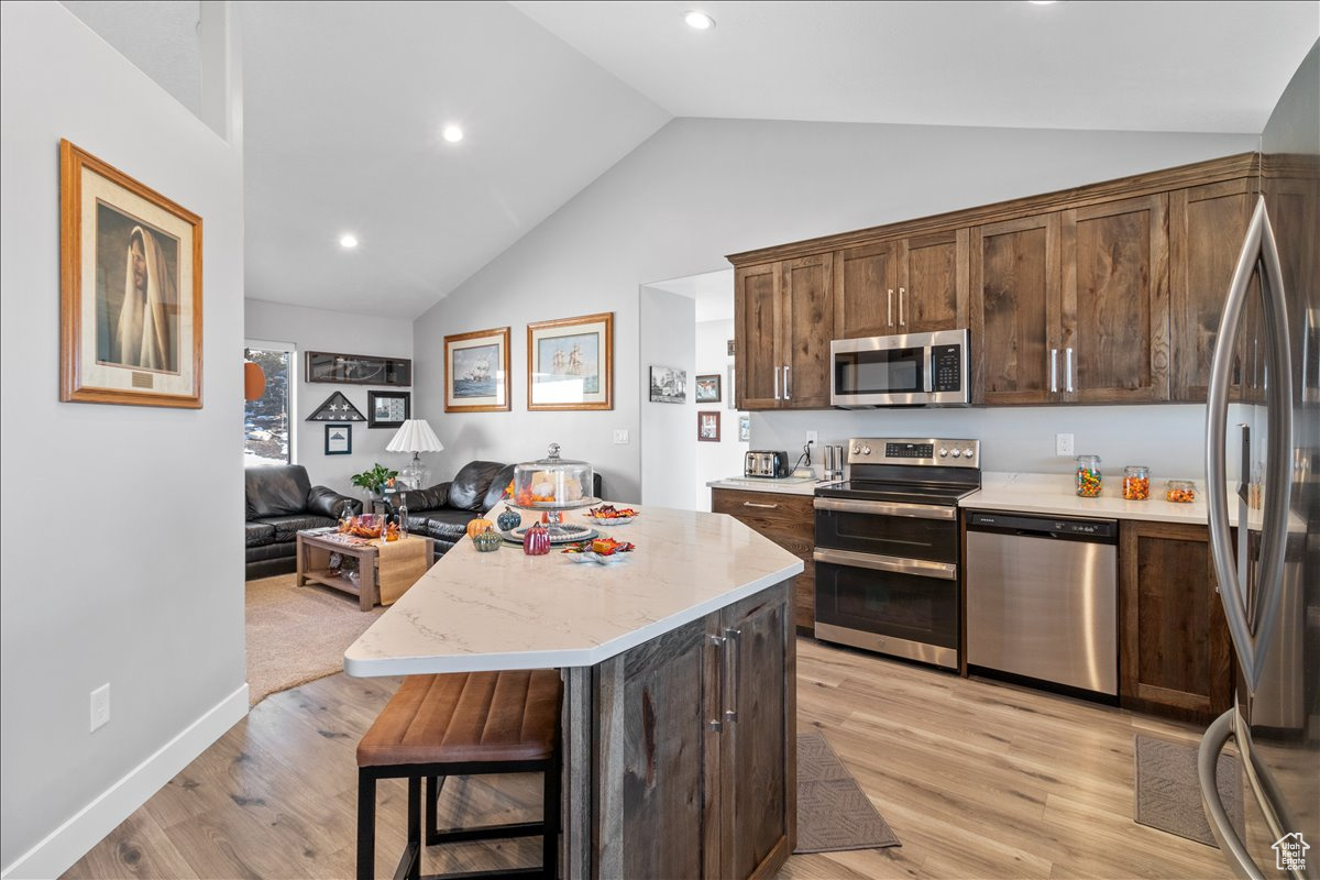 Kitchen island, stainless steal appliances featuring luxury vinyl flooring