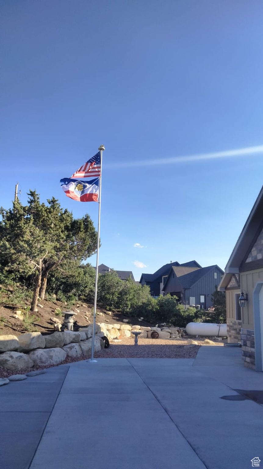 Front yard featuring bolders, flag pole and concrete leading to front porch area