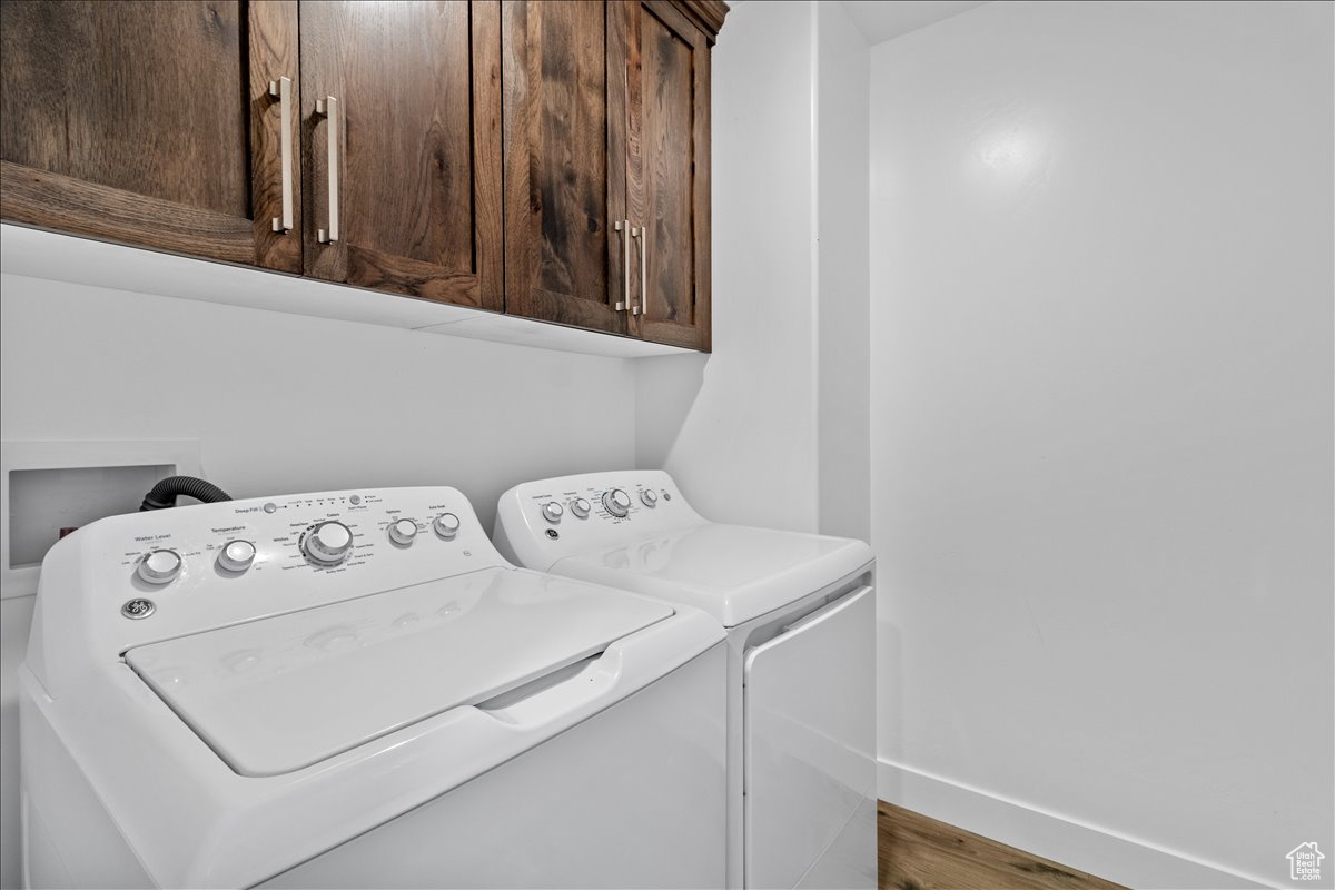 Main floor laundry room featuring high - end cabinets and luxury vinyl flooring