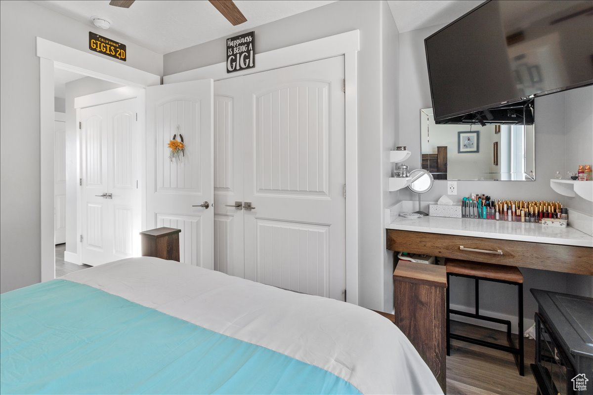 Main floor bedroom featuring carpet flooring and sit down vanity with mirror and quartz top and same cabinet material