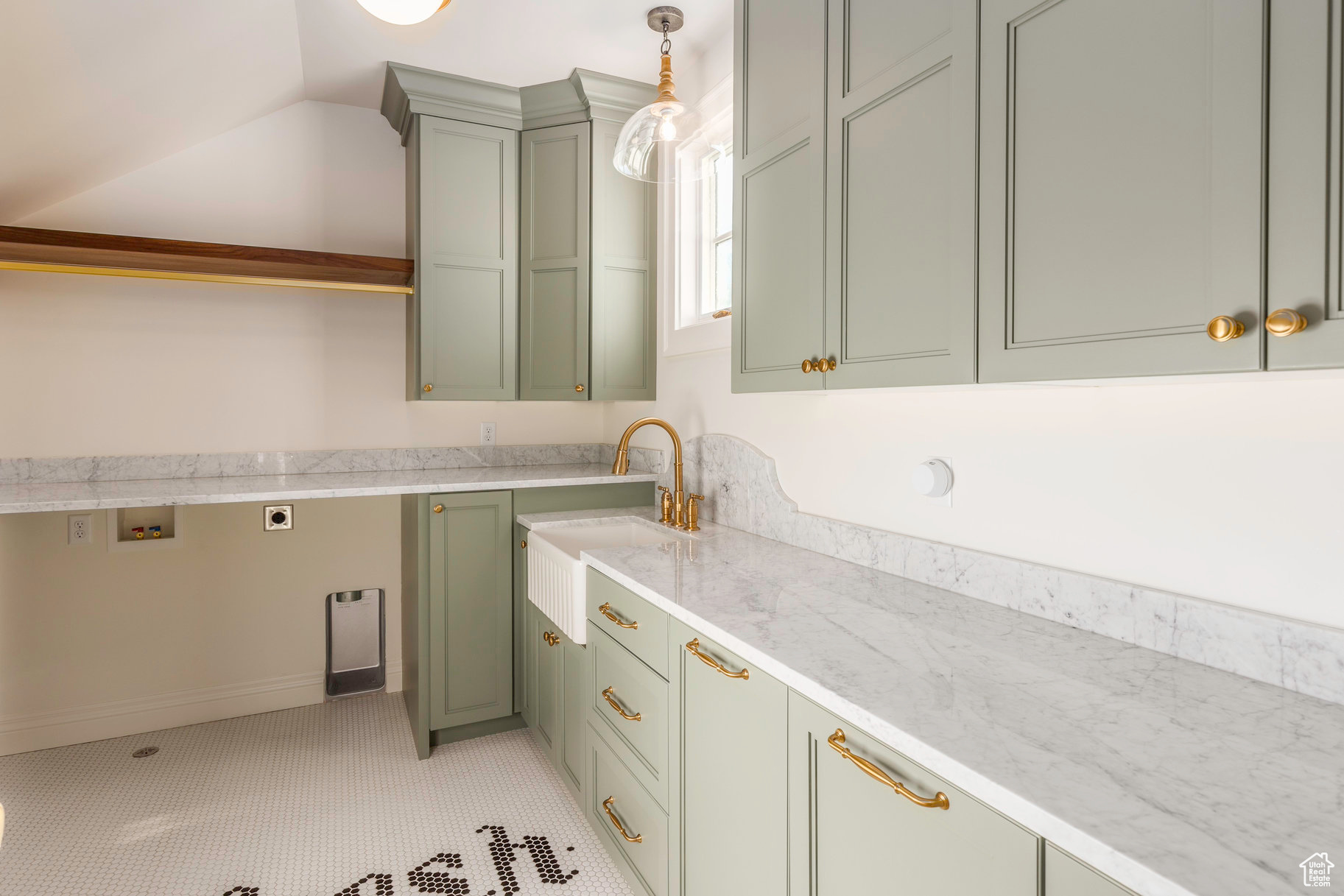 Kitchen with decorative light fixtures, light stone countertops, and sink