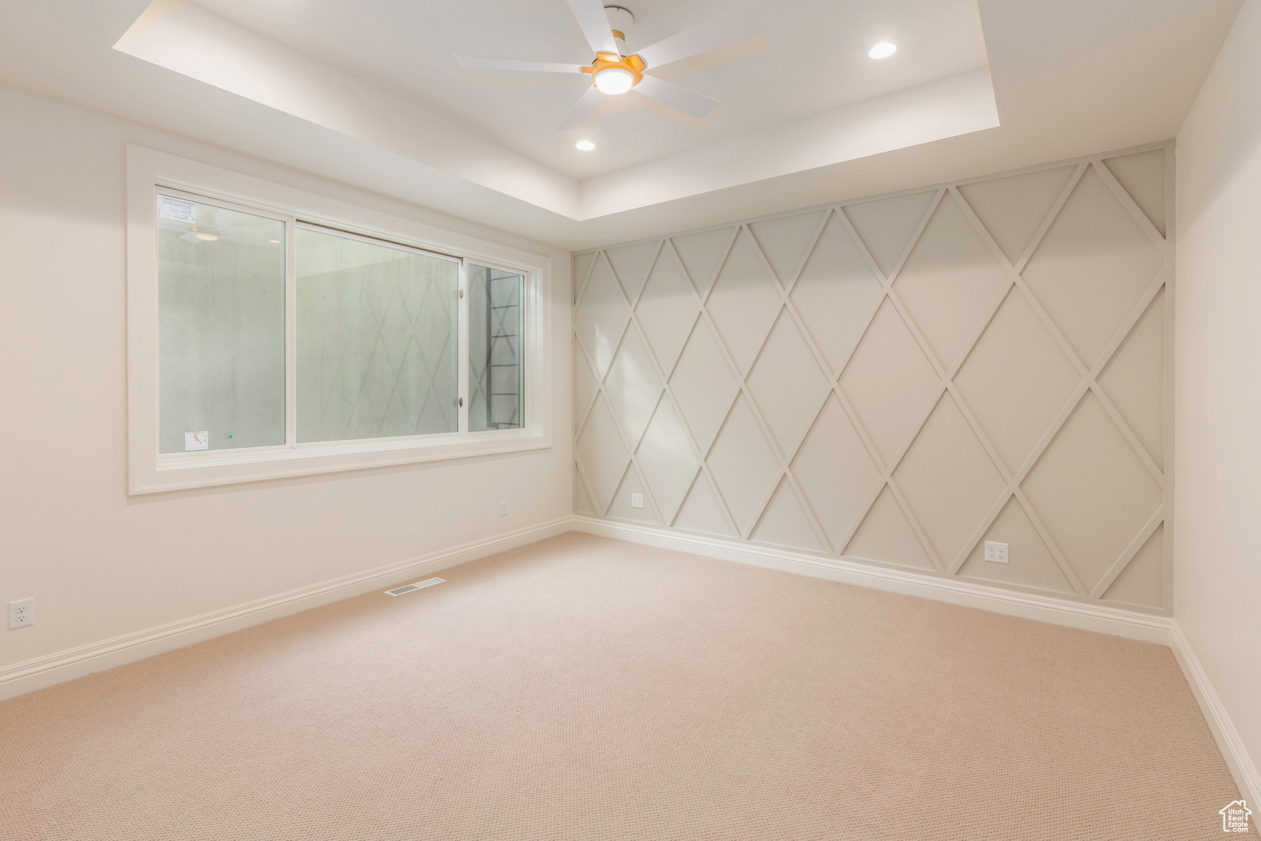 Empty room featuring carpet, a tray ceiling, and ceiling fan