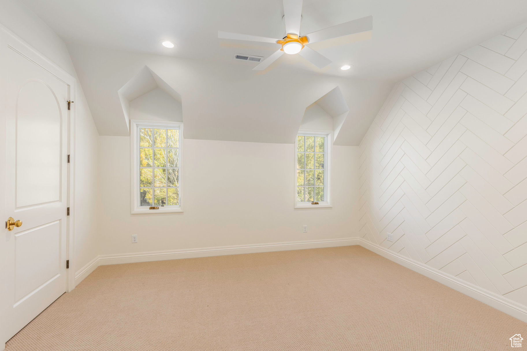 Additional living space with light carpet, a wealth of natural light, lofted ceiling, and ceiling fan