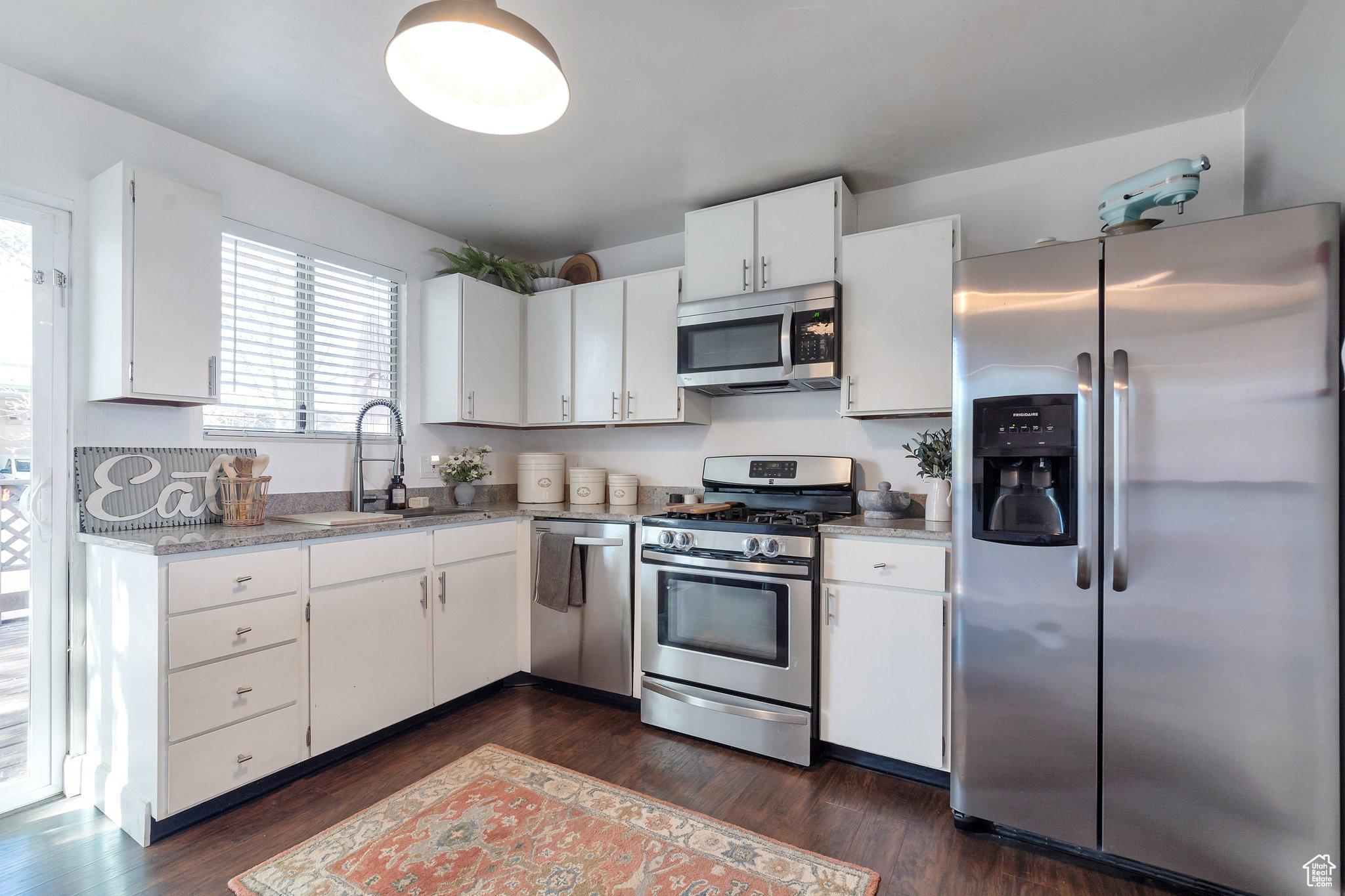 Kitchen with white cabinets, stainless steel appliances, sink, and dark hardwood / wood-style flooring