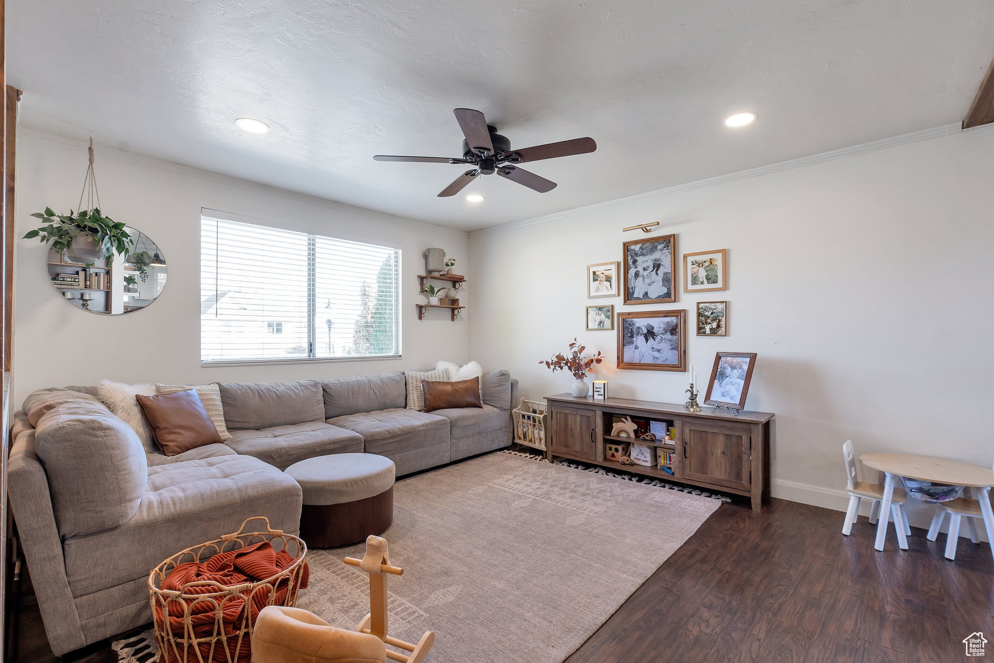 Living room featuring dark hardwood / wood-style flooring, ceiling fan, and crown molding