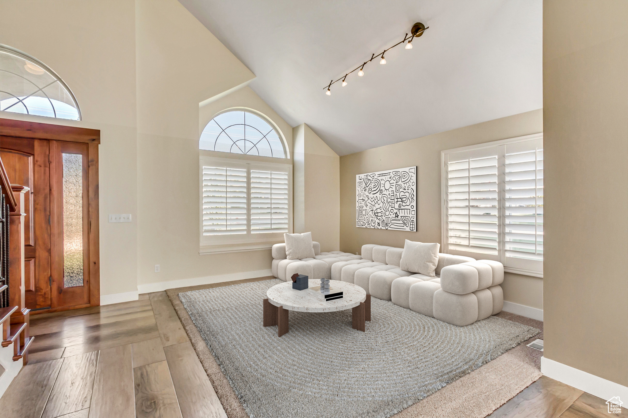 Living room featuring hardwood / wood-style floors, rail lighting, and high vaulted ceiling