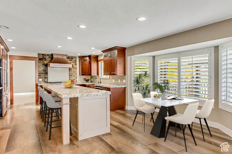 Kitchen with sink, tasteful backsplash, light stone counters, light hardwood / wood-style floors