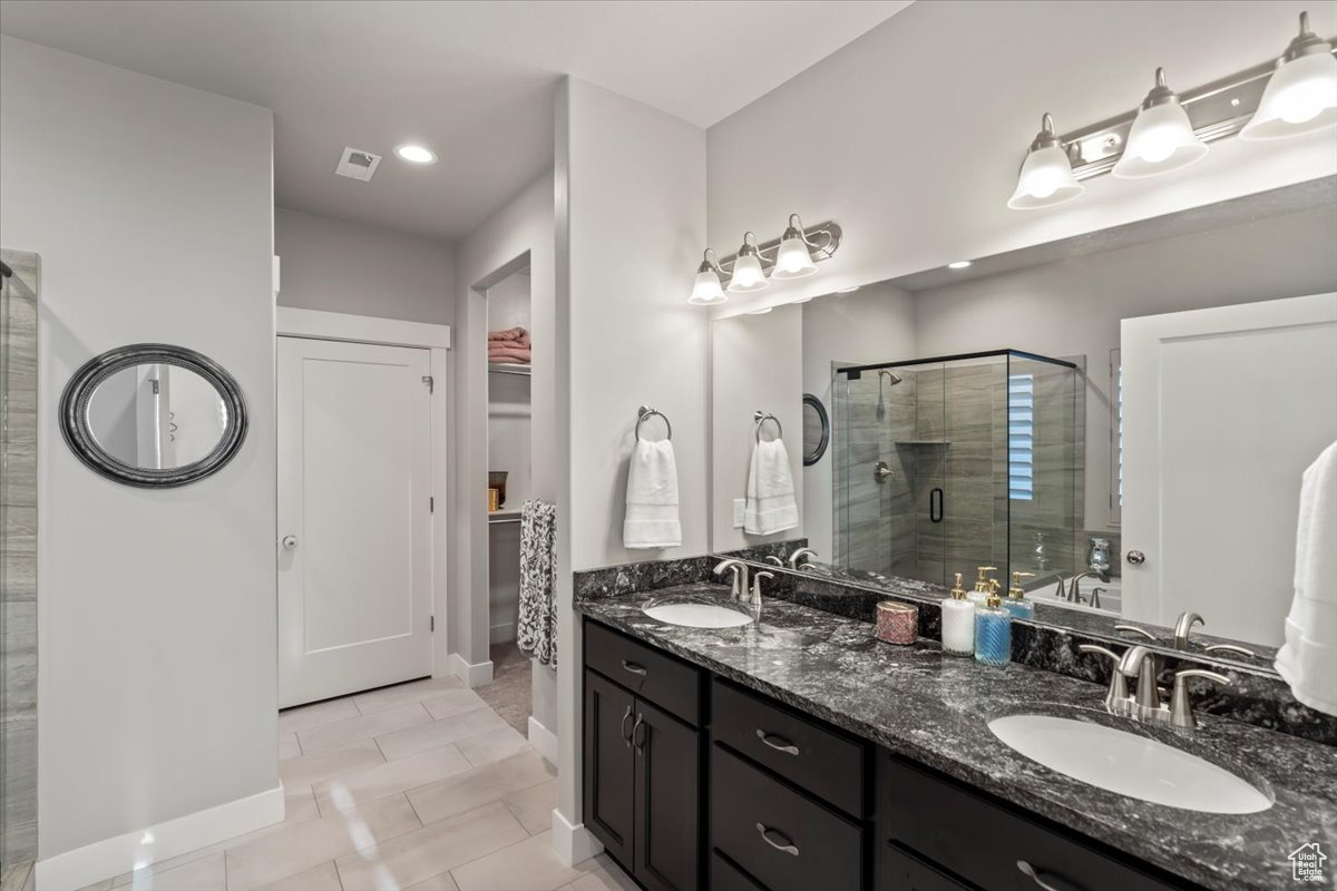 Bathroom with tile patterned floors, vanity, and a shower with shower door