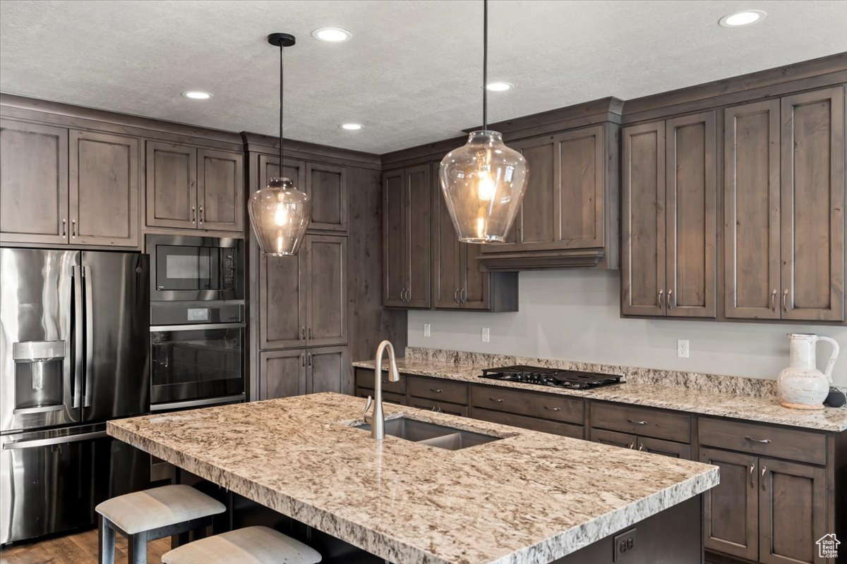 Kitchen with a kitchen breakfast bar, sink, decorative light fixtures, and black appliances