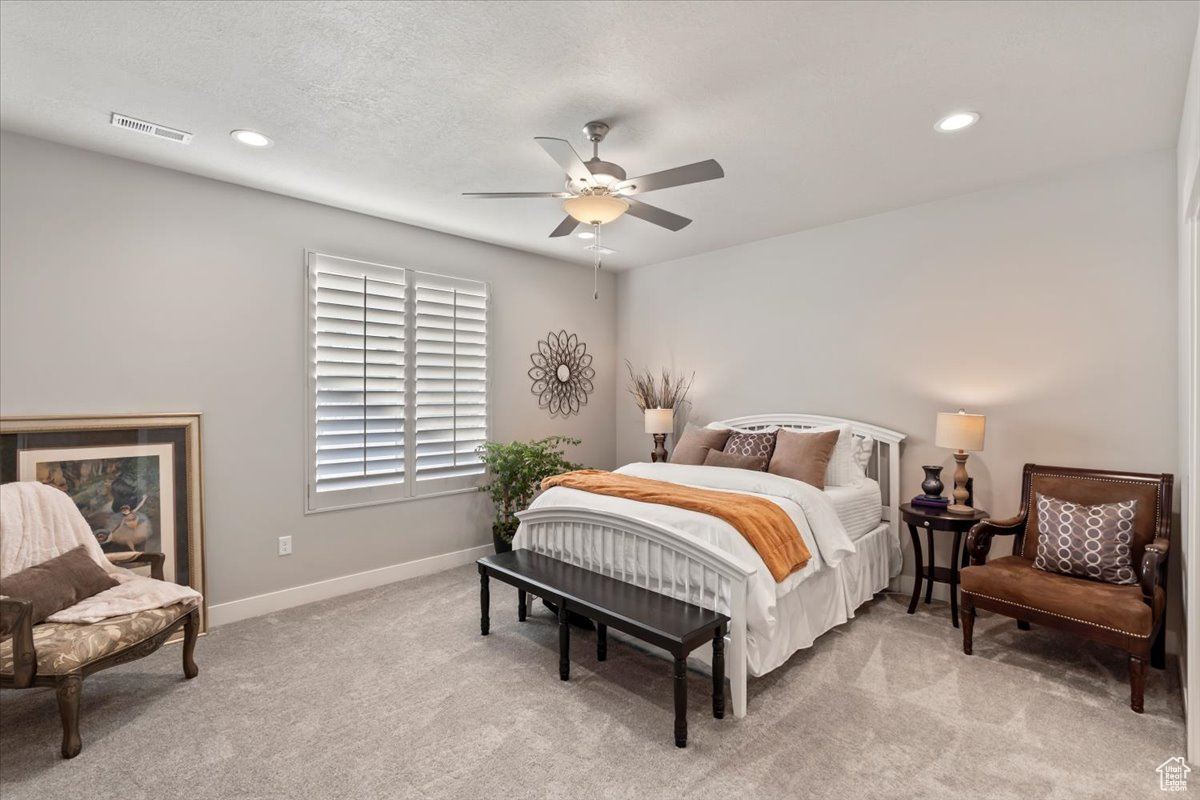 Bedroom featuring ceiling fan, light colored carpet, and a textured ceiling