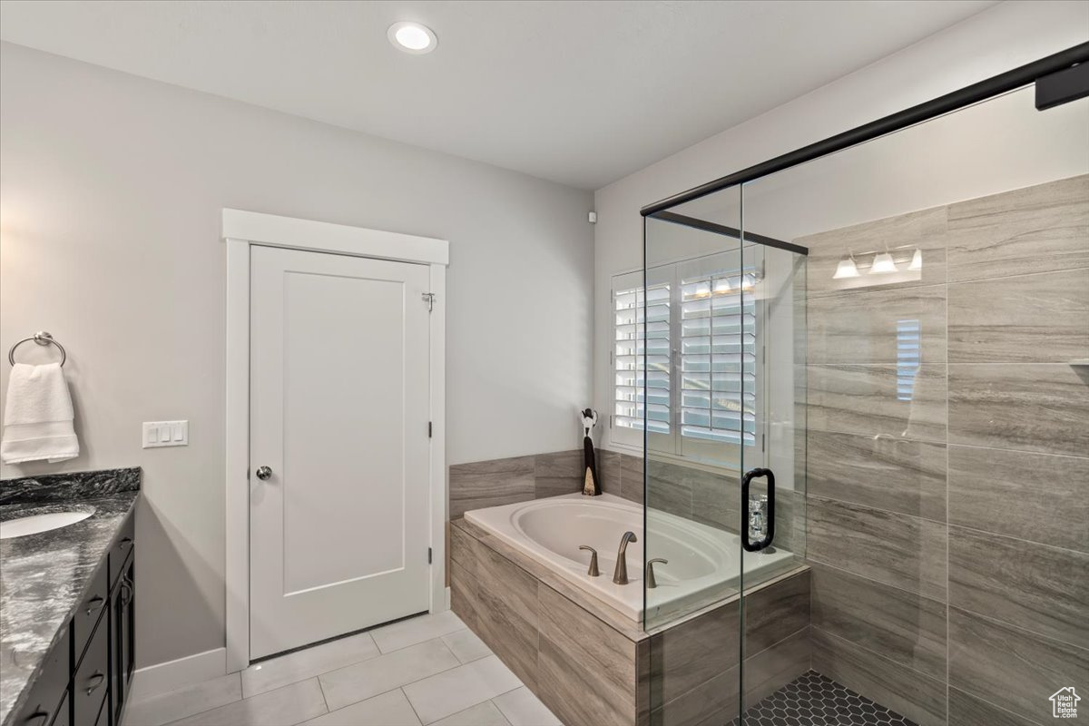 Bathroom featuring plus walk in shower, vanity, and tile patterned flooring