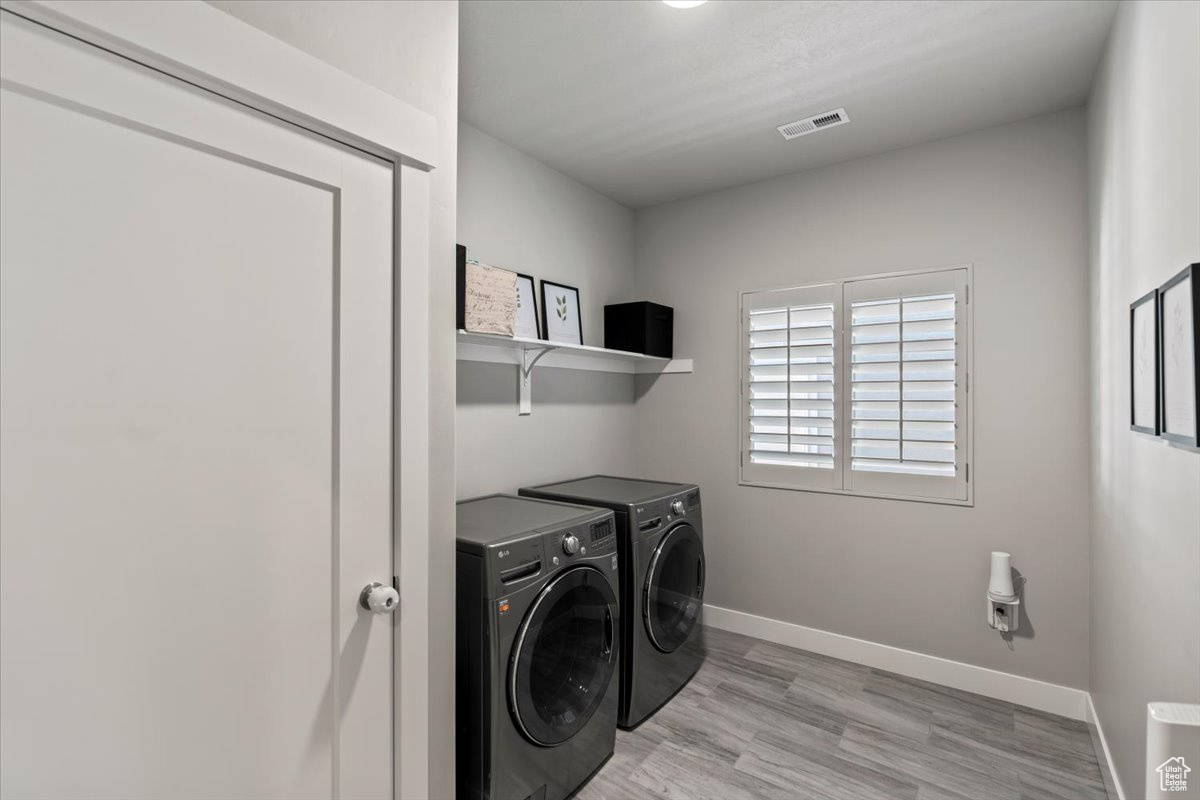 Laundry room featuring independent washer and dryer and light hardwood / wood-style flooring