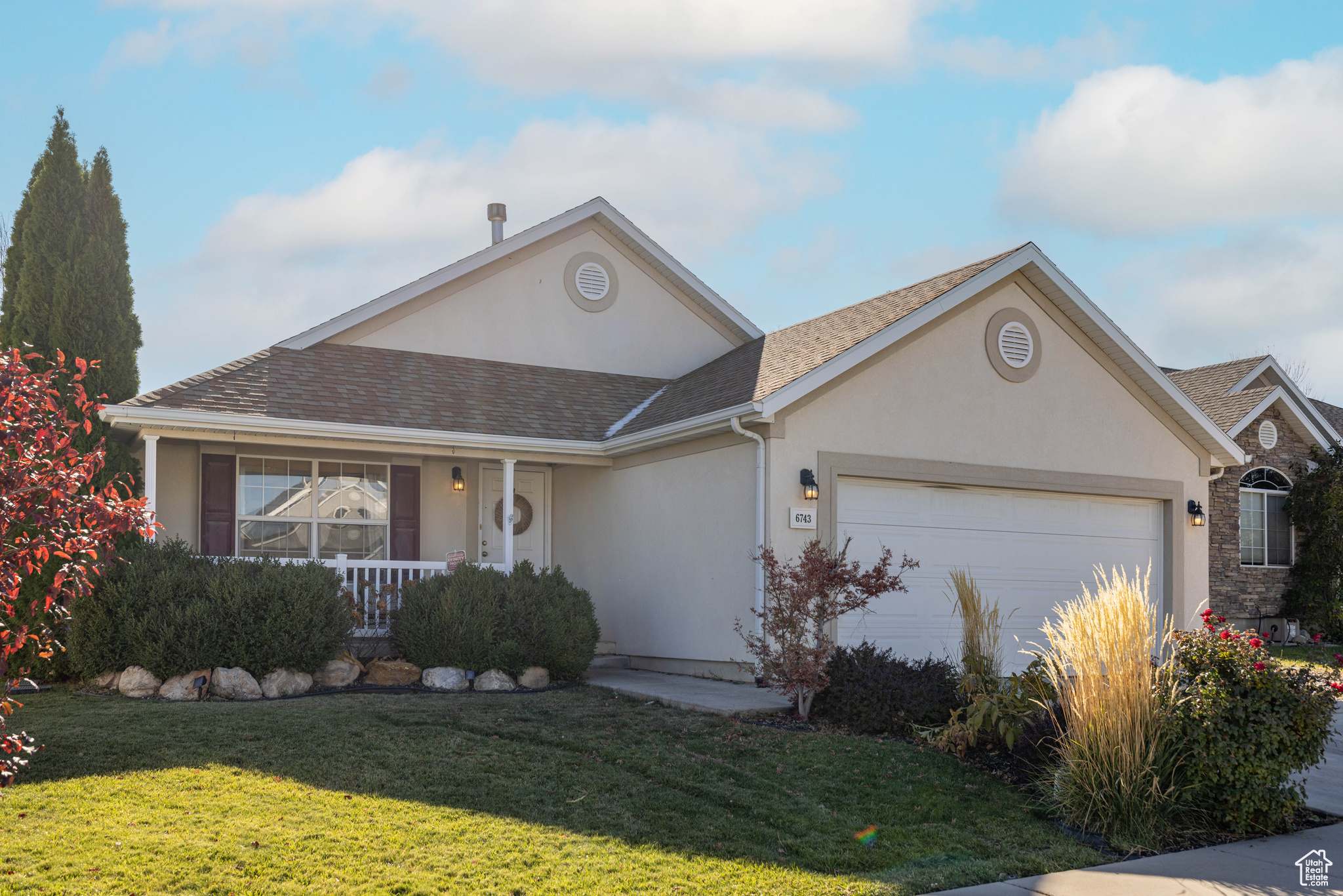 Ranch-style house featuring a garage, a front yard, and covered porch