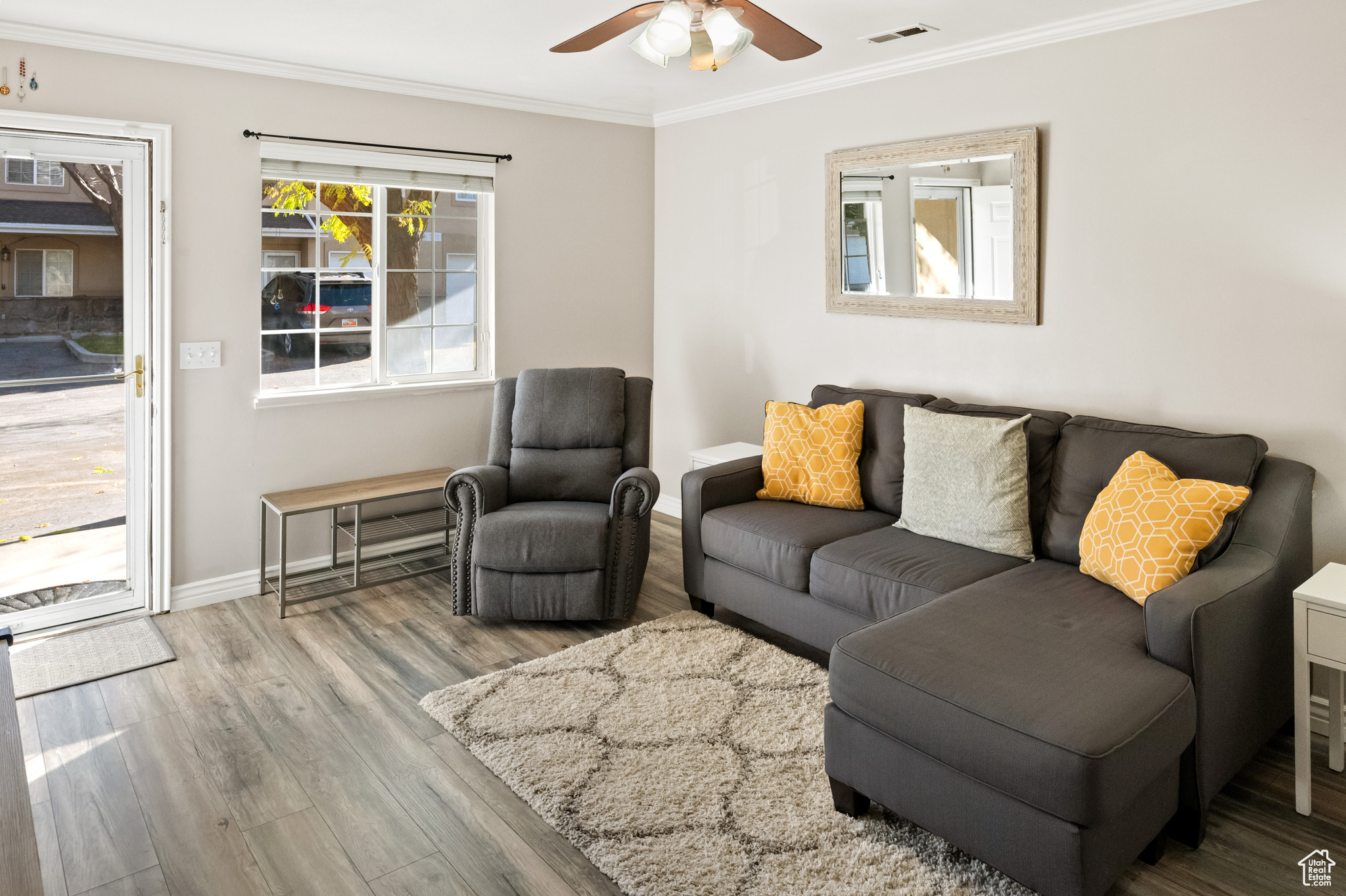 Living room with  laminate flooring, ceiling fan, and crown molding