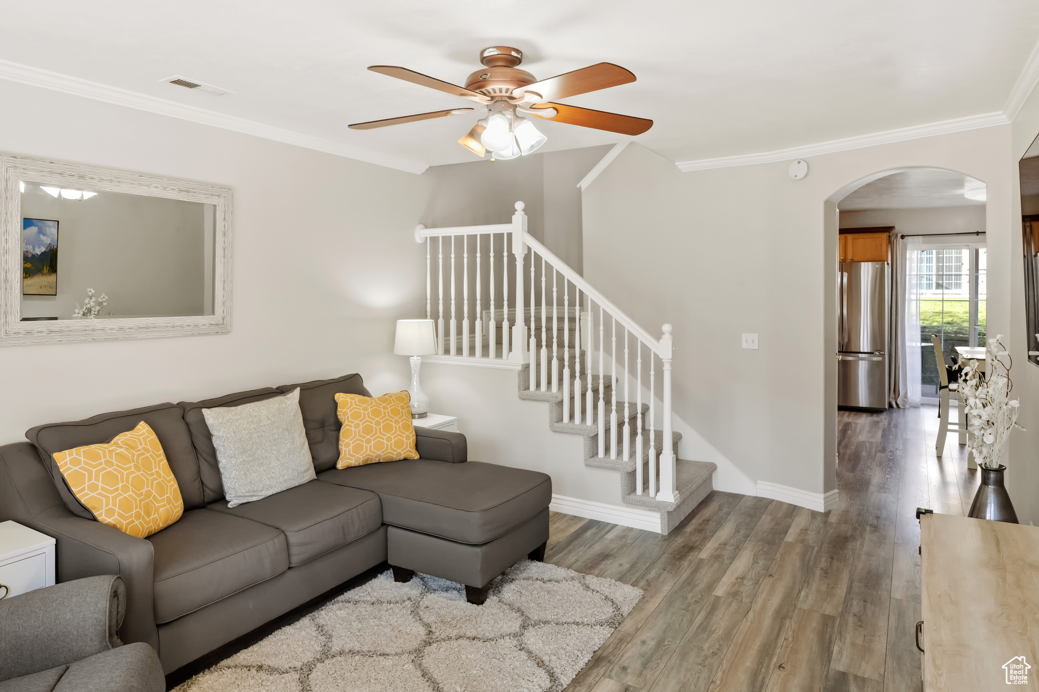 Living room with laminate flooring, ceiling fan, and ornamental molding