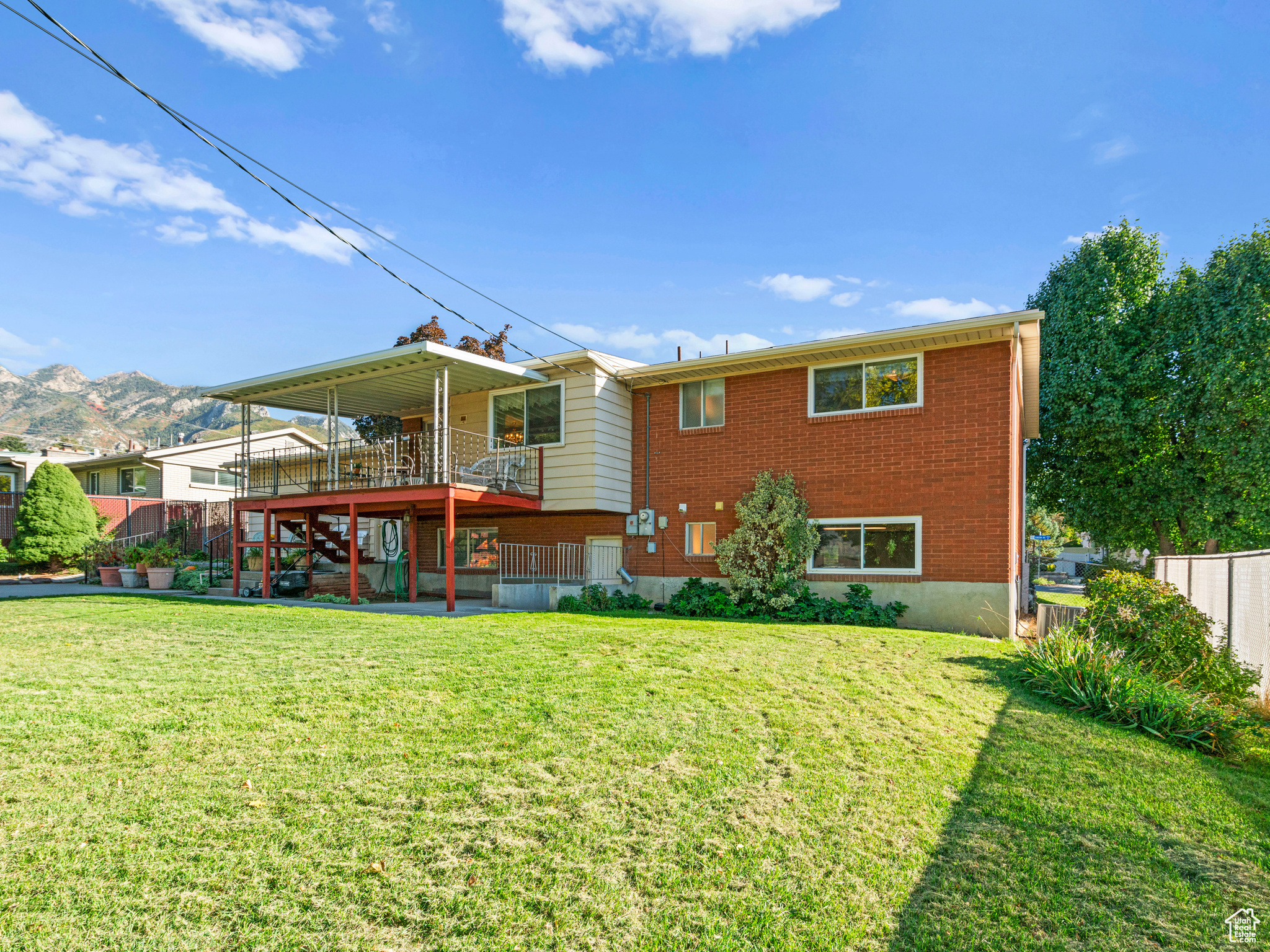 Rear view of house with a deck with mountain view, a lawn, and a patio