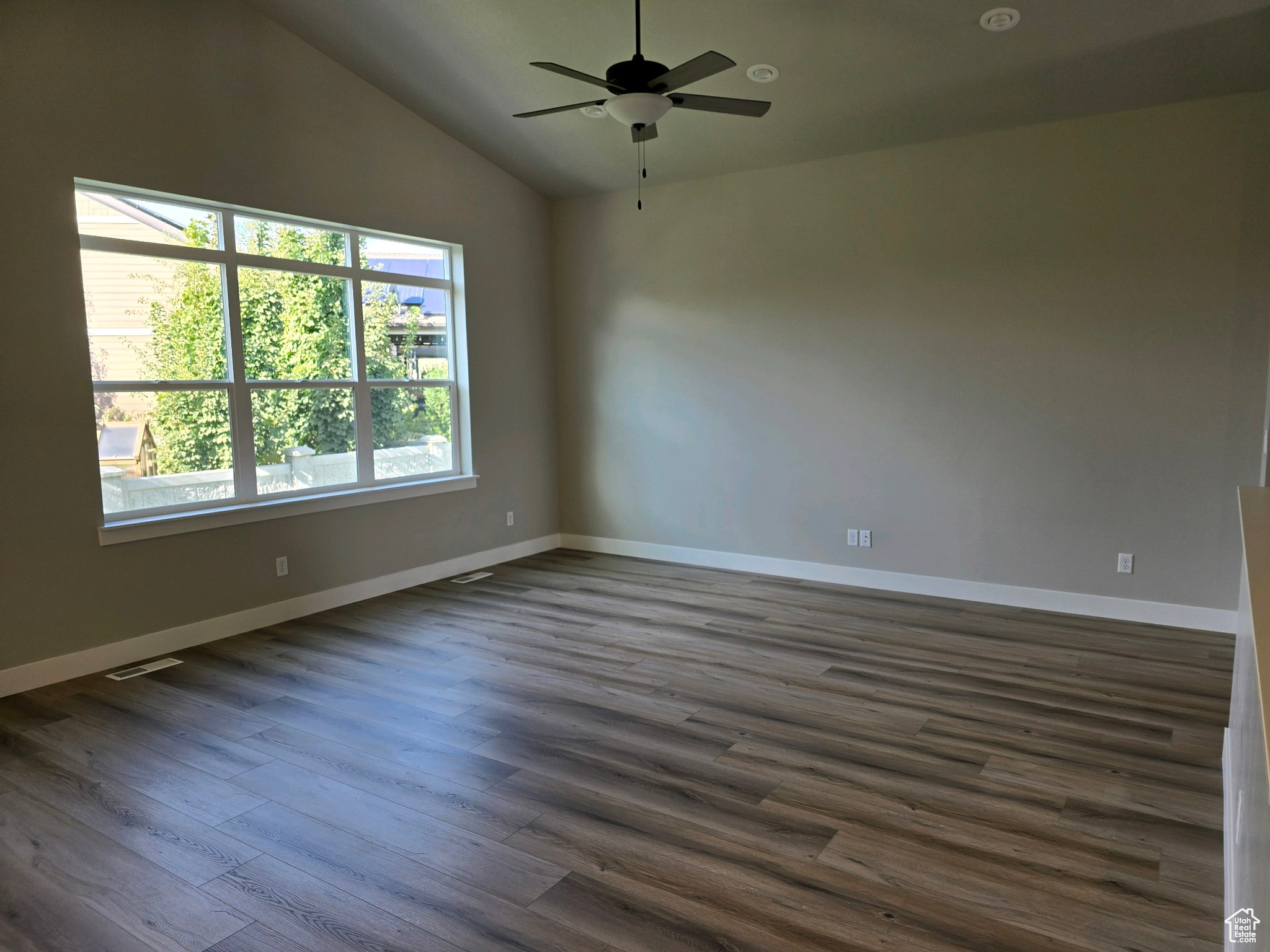 Unfurnished room with dark hardwood / wood-style flooring, vaulted ceiling, and ceiling fan