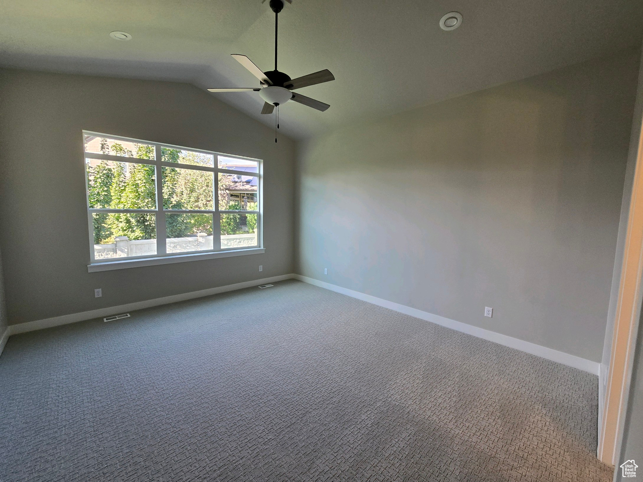 Unfurnished room featuring ceiling fan, carpet flooring, and vaulted ceiling