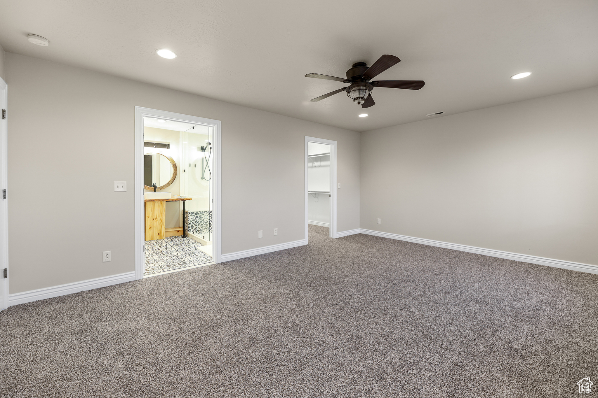 Primary Suite featuring a closet, a spacious closet, ensuite bath, carpet flooring, and ceiling fan