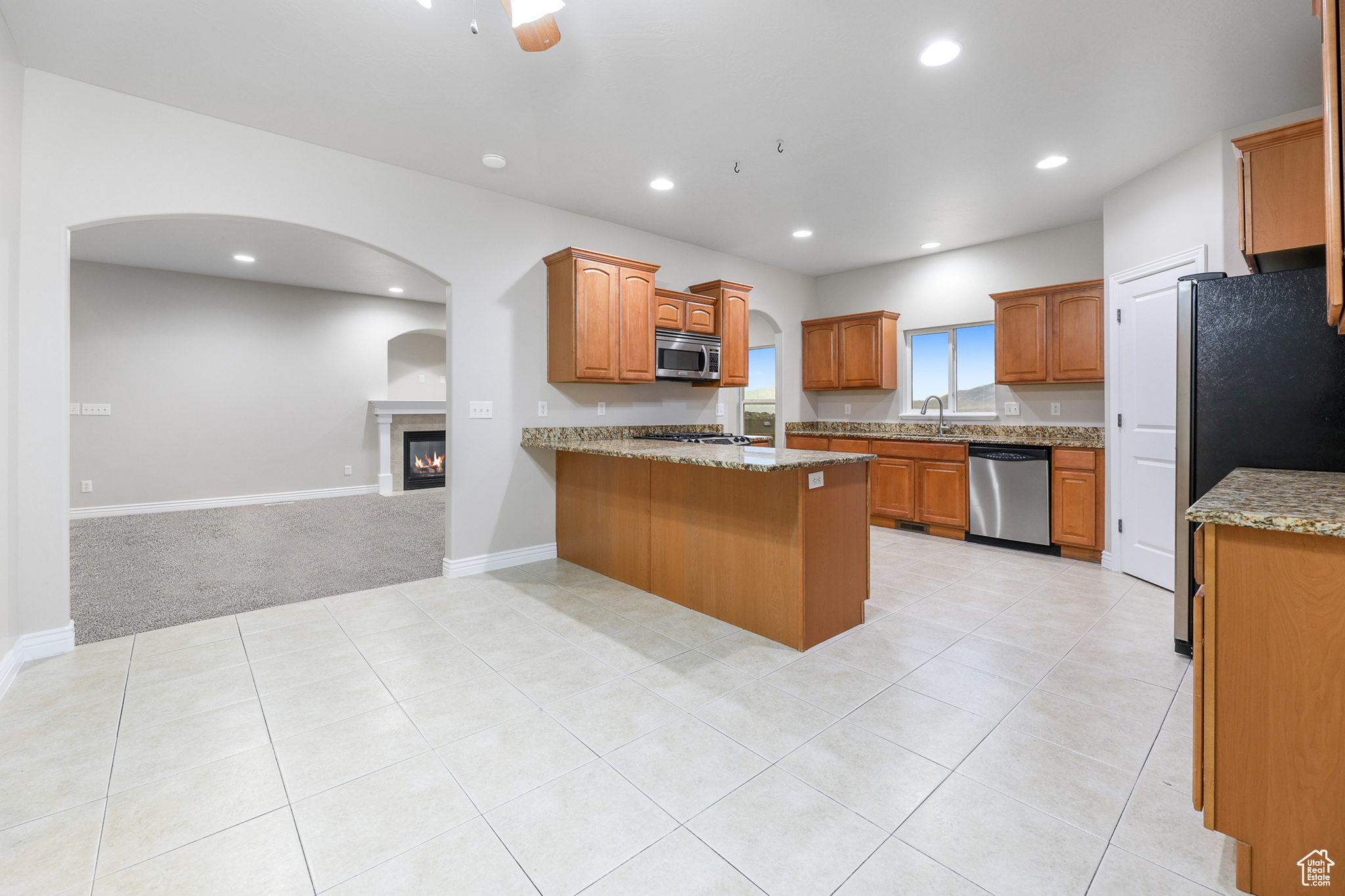 Kitchen with appliances with stainless steel finishes, light carpet, sink, kitchen peninsula, and ceiling fan