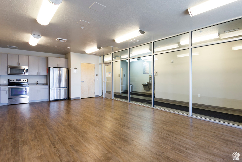 Clubhouse kitchen featuring stainless steel appliances, a textured ceiling, and dark hardwood / wood-style flooring