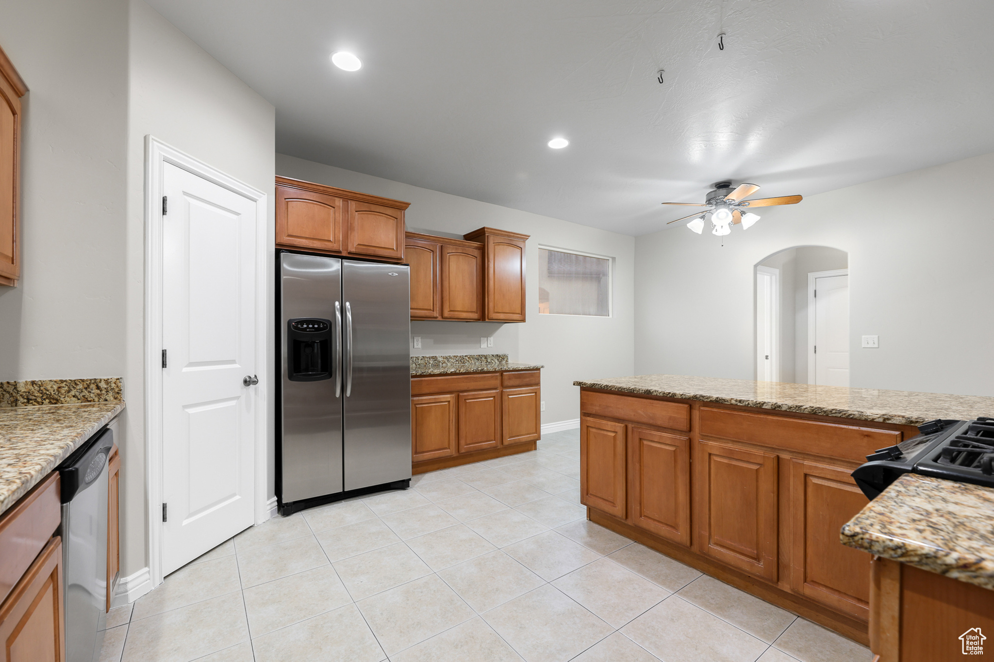 Kitchen featuring ceiling fan, light tile patterned floors, light stone counters, and appliances with stainless steel finishes