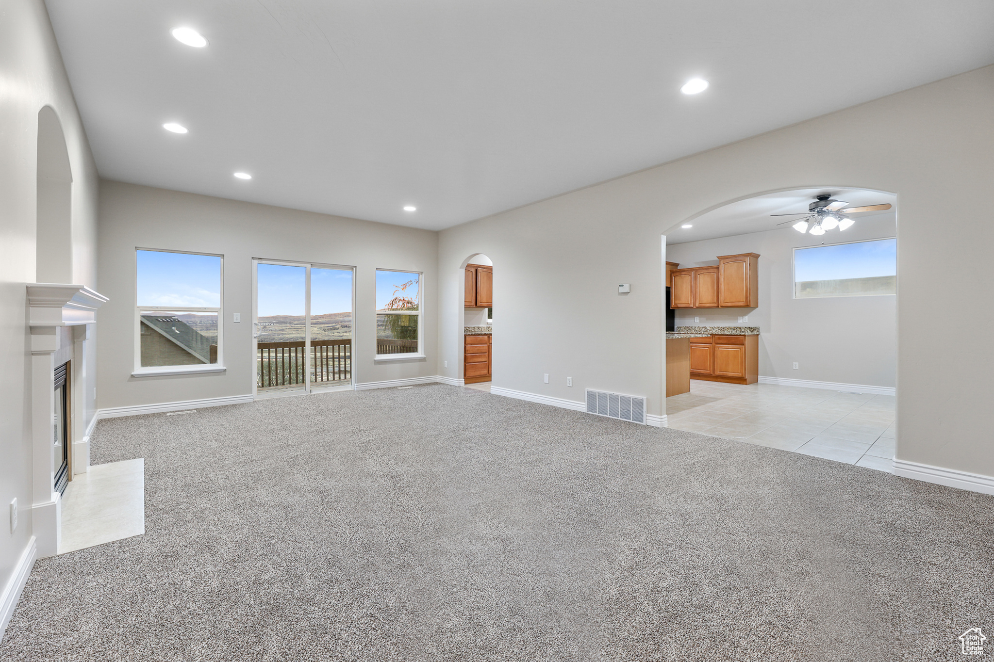 Unfurnished living room with light carpet and ceiling fan