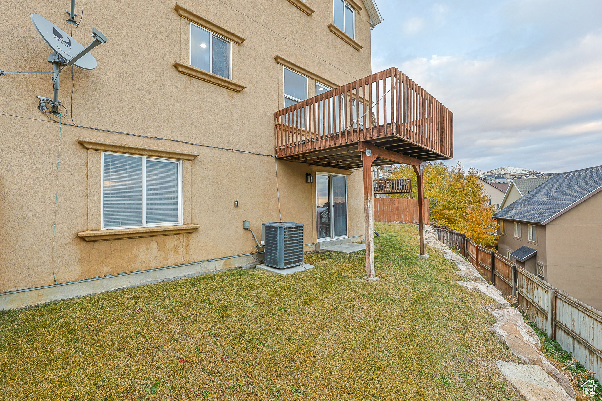 Rear view of property featuring a deck, central air condition unit, and a yard