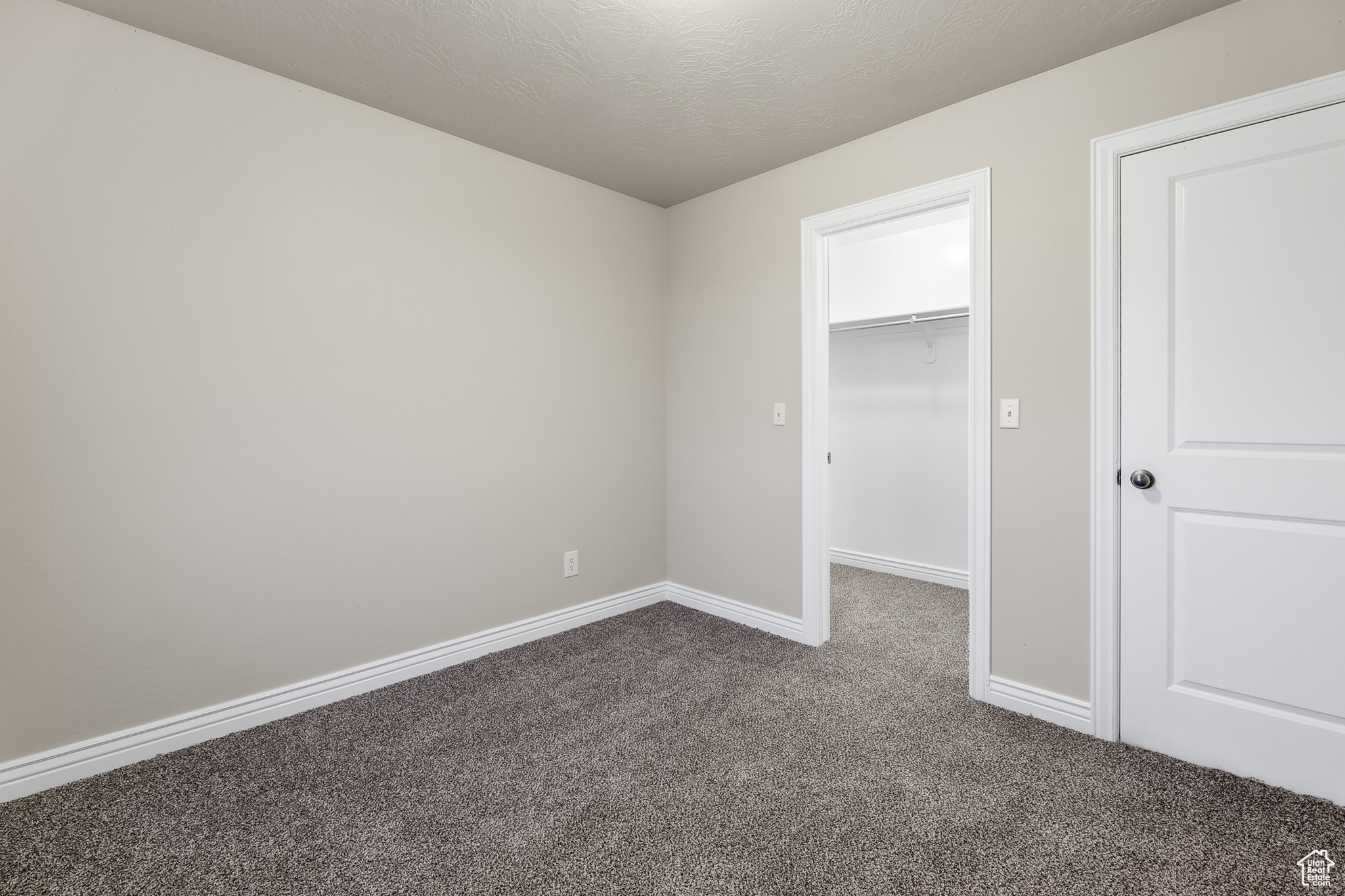 Unfurnished bedroom with a closet, carpet, a spacious closet, and a textured ceiling