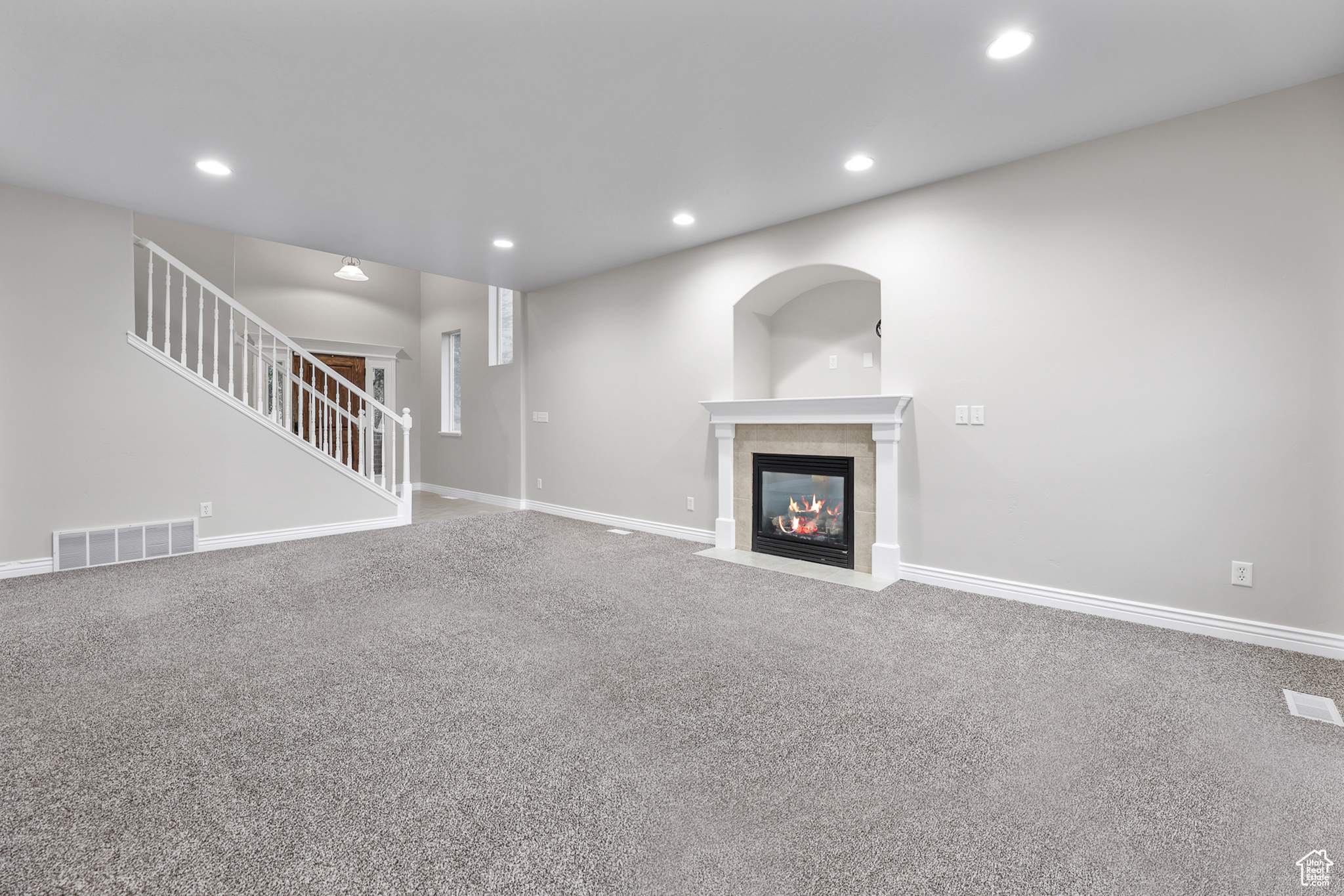 Unfurnished living room featuring carpet floors and a tile fireplace