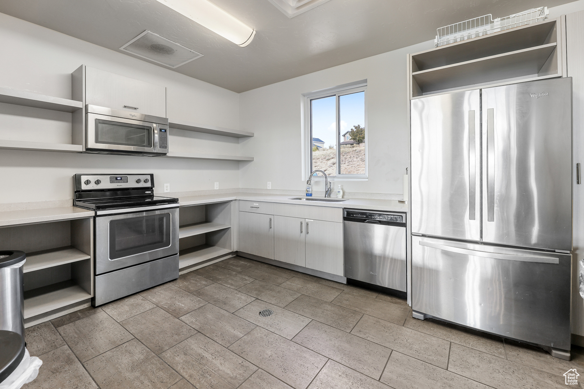 Clubhouse kitchen featuring white cabinetry, stainless steel appliances, and sink