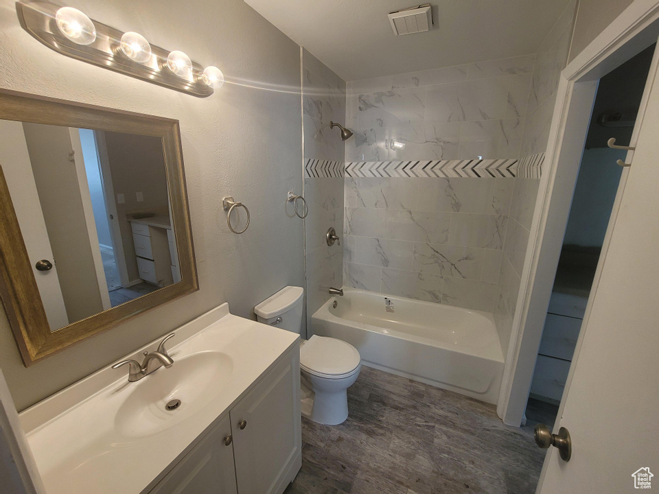 Full bathroom featuring toilet, vanity, tiled shower / bath, and hardwood / wood-style flooring